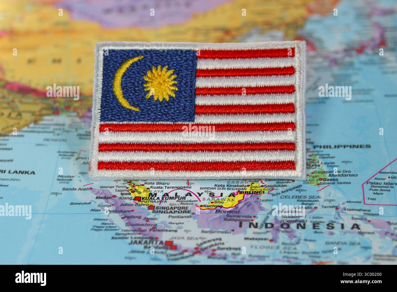 Bandiera malese ecologica realizzata in filo e tessuto, posta sulla mappa del mondo che segna la Malesia nel sud-est asiatico. Concetto di viaggio e destinazione. Foto Stock