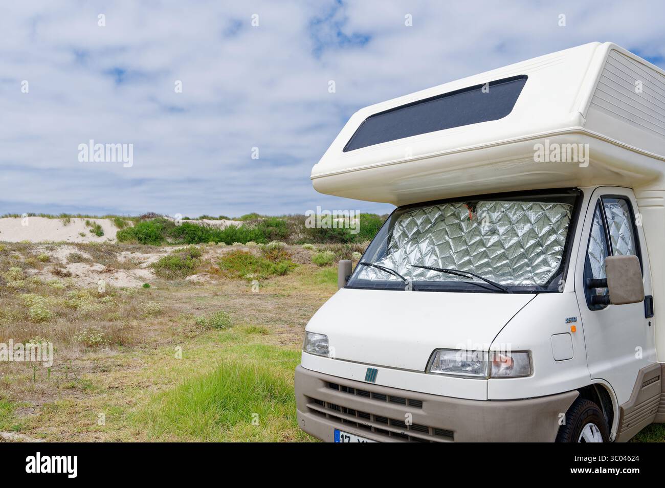Camper parcheggiato lungo dune di sabbia, che proteggono l'interno dal sole con coperture riflettenti Foto Stock