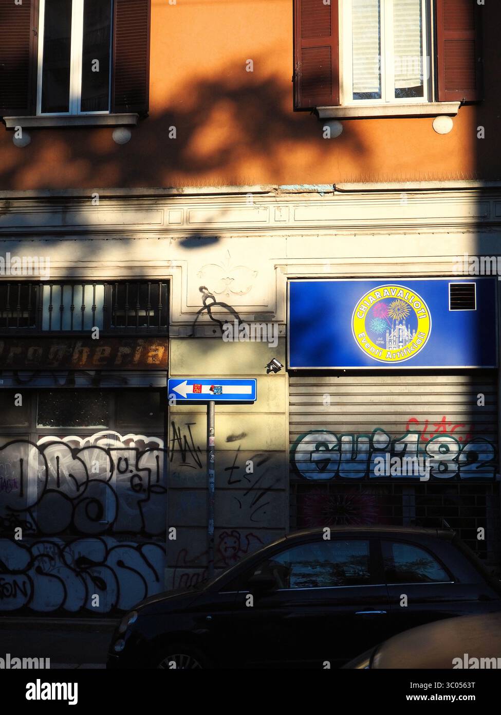 Strada di Milano ricoperta di graffiti, con luce solare dappata e negozi vintage Foto Stock