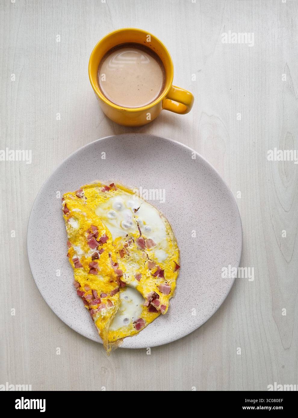 Colazione con caffè. Tazza gialla di caffè e omelette gialle su un piatto beige. Foto Stock