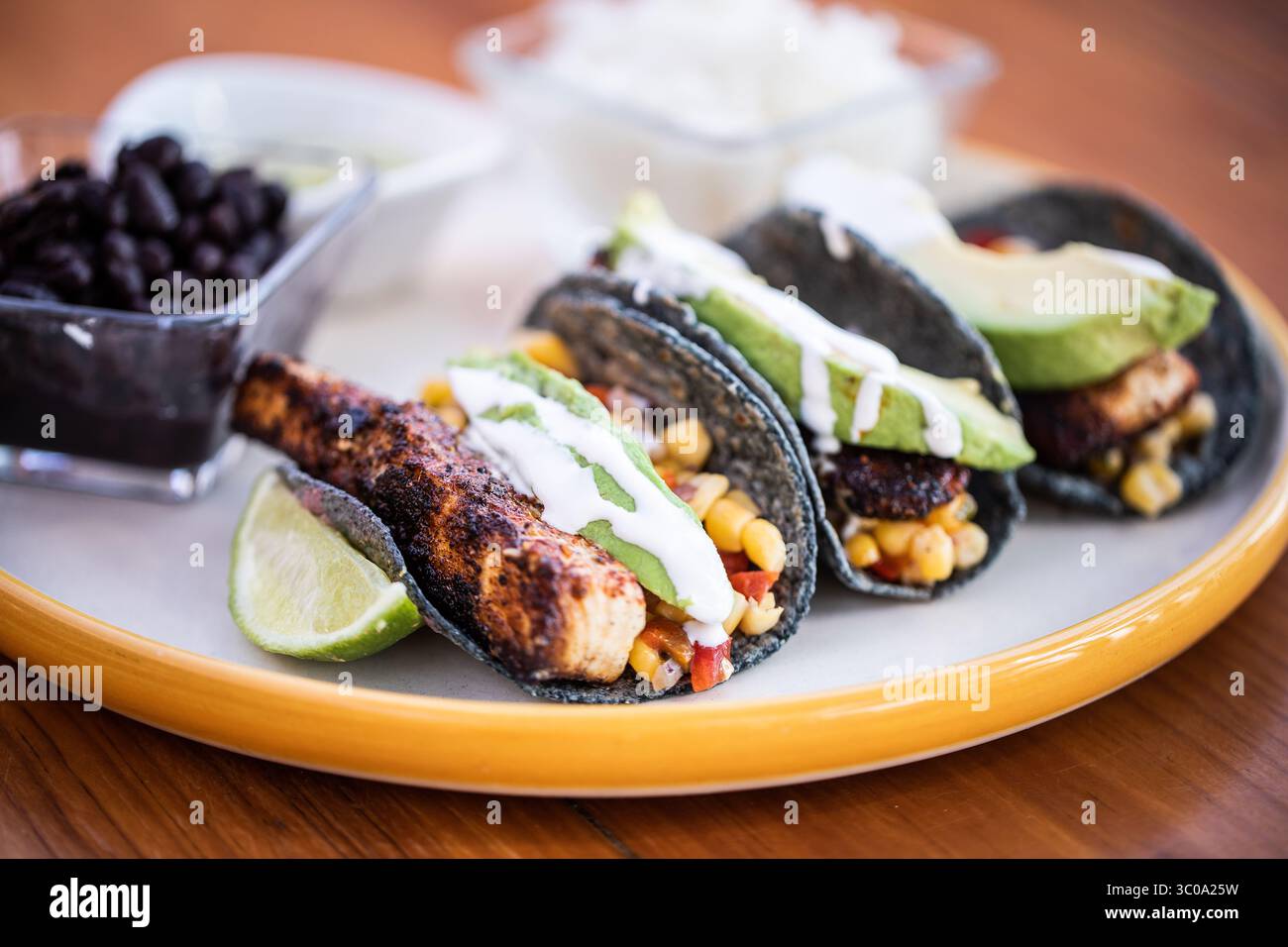 Tre Tacos di pesce con avocado e panna acida Foto Stock