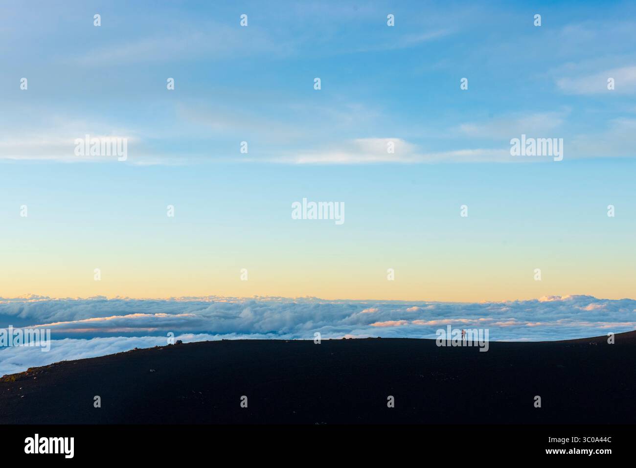 Una persona si arrampica su un crinale sopra un mare di nuvole Foto Stock