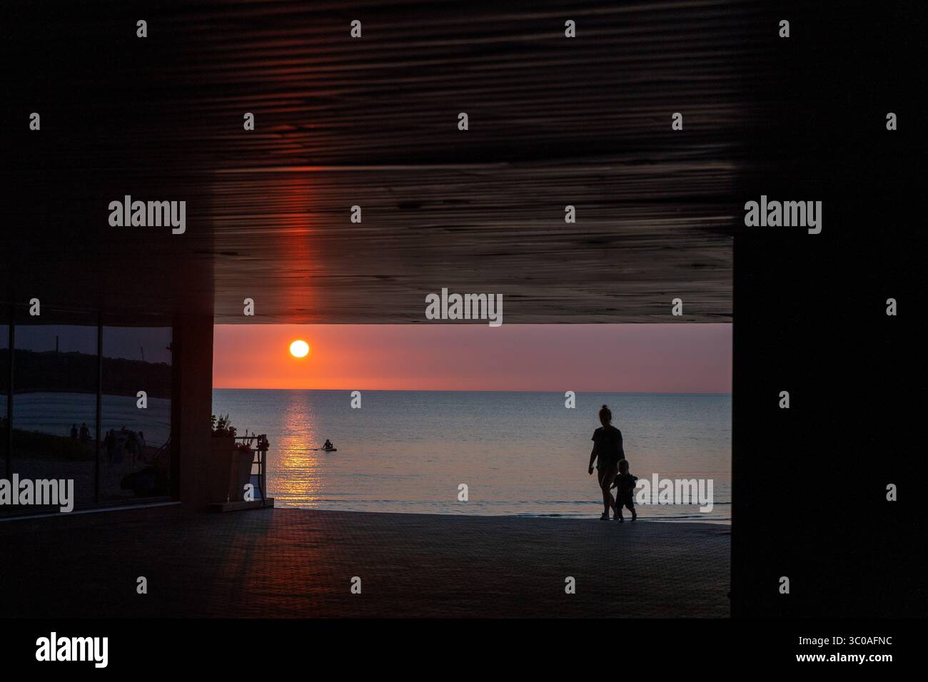 Sagoma dell'uomo in piedi vicino al mare al tramonto: Pace, connessione, libertà, natura, riflesso crepuscolare, tranquillo Foto Stock