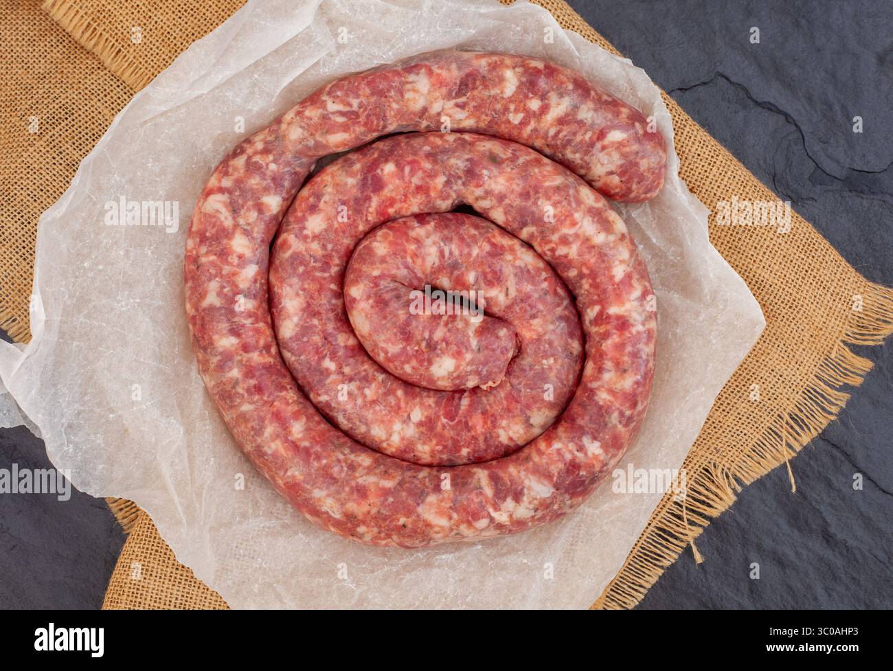 Grezze boerewors sudafricani a forma di spirale su ardesia e ardesia nera Foto Stock