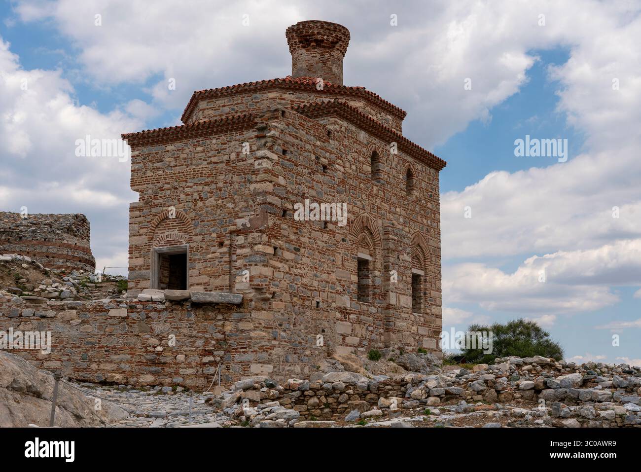 Al confine della collina Ayasoluk di Selcu, la moschea di Kale sorge in pietra serena, il suo minareto aspira tranquillamente sopra le stradine tortuose e l'erba illuminata dal sole. Foto Stock