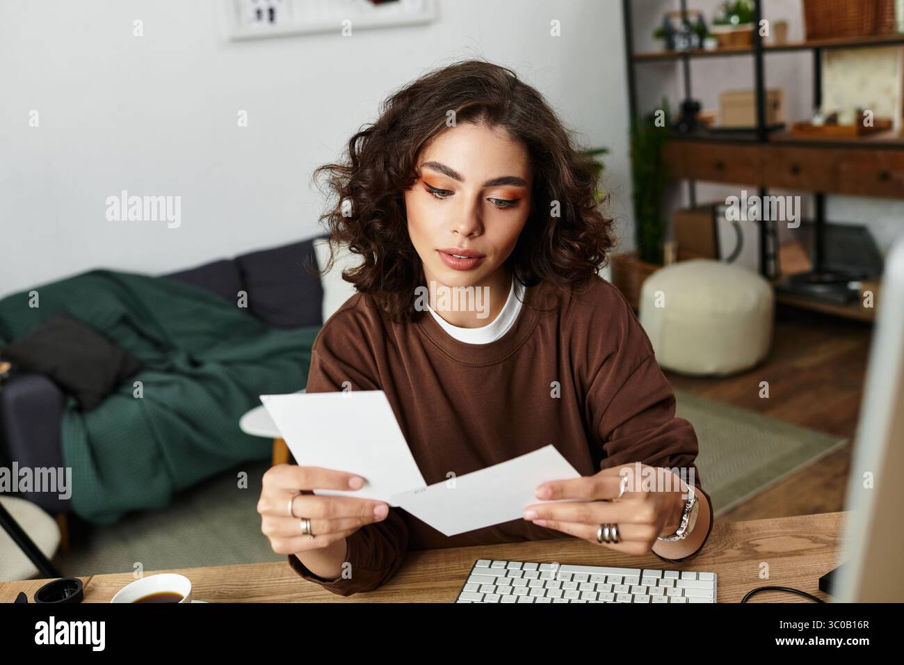 Una giovane donna rivede il suo lavoro creativo in un accogliente ambiente di ufficio domestico. Foto Stock