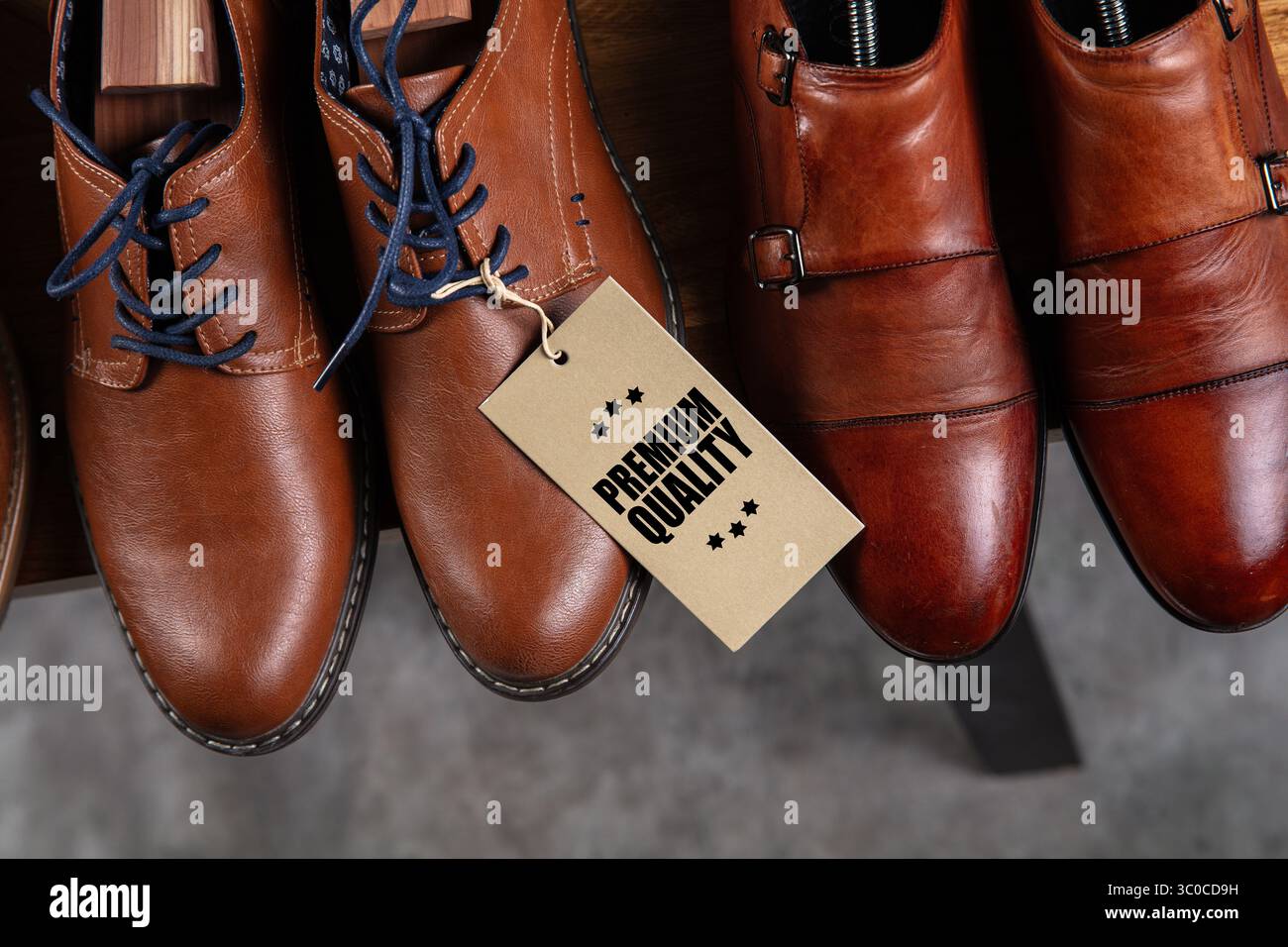 Vista dall'alto degli eleganti abiti in pelle marrone disposti in modo ordinato su un ripiano in legno. Una coppia presenta un'etichetta di "qualità Premium" visibile applicata alla centralina lac Foto Stock