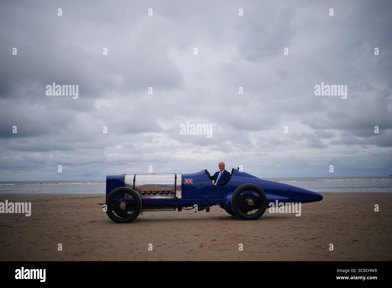Don Wales, nipote di Sir Malcolm Campbell, con la Blue Bird Land Speed record car durante un evento centenario a Pendine Sands, Carmarthen, Galles del Sud. Il 21 luglio segna un secolo da quando Blue Bird ha fatto irruzione in Pendine Sands, stabilendo un nuovo record mondiale di velocità terrestre a 150 km/h (76 mph). Data foto: Lunedì 21 luglio 2025. Foto Stock