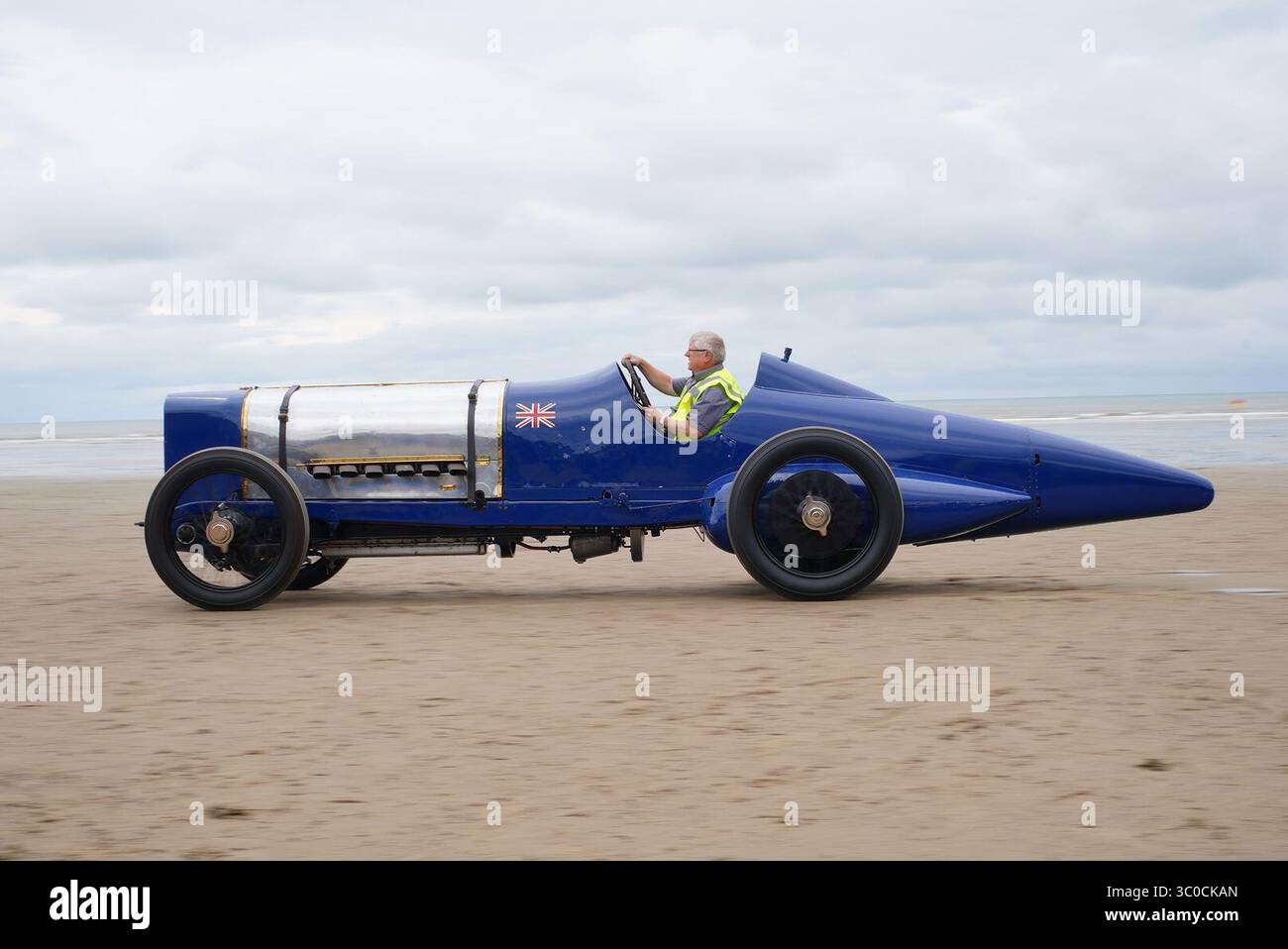Un ingegnere guida la Blue Bird Land Speed record car durante un evento centenario a Pendine Sands, Carmarthen, nel Galles del Sud. Il 21 luglio segna un secolo da quando Blue Bird ha fatto irruzione in Pendine Sands, stabilendo un nuovo record mondiale di velocità terrestre a 150 km/h (76 mph). Data foto: Lunedì 21 luglio 2025. Foto Stock