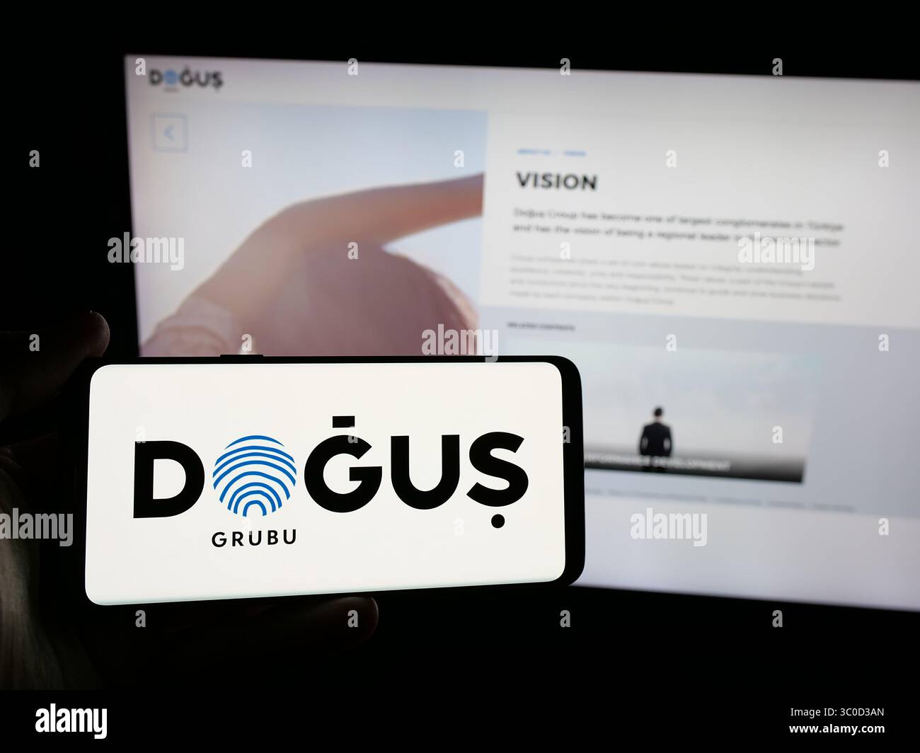 Stoccarda, Germania - 05-16-2025: Persona con smartphone con logo della società turca Dogus Holding A.S. sullo schermo davanti al sito web. Foto Stock