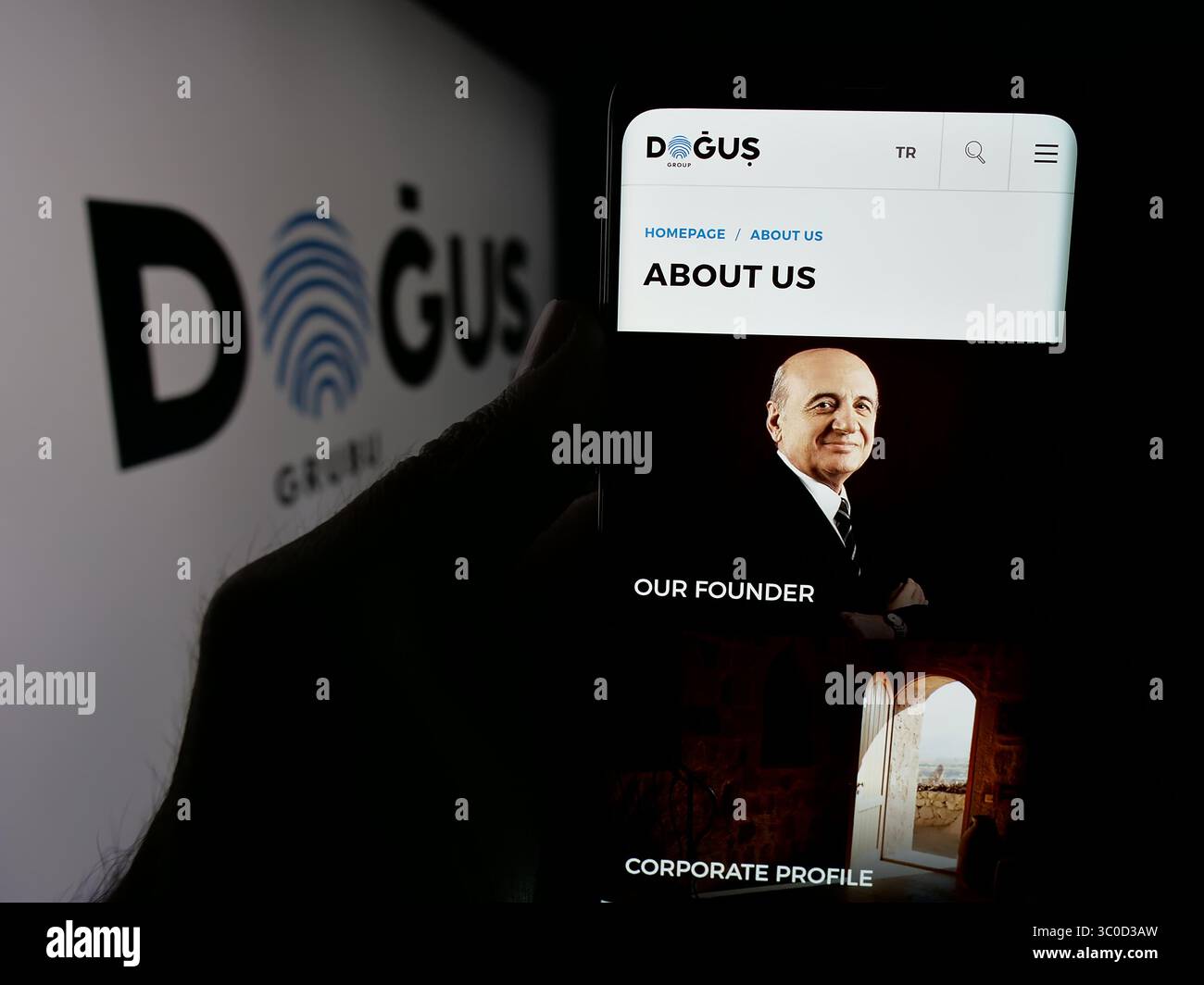 Stoccarda, Germania - 05-16-2025: Persona con smartphone e pagina web della società turca Dogus Holding A.S. sullo schermo davanti al logo. Foto Stock