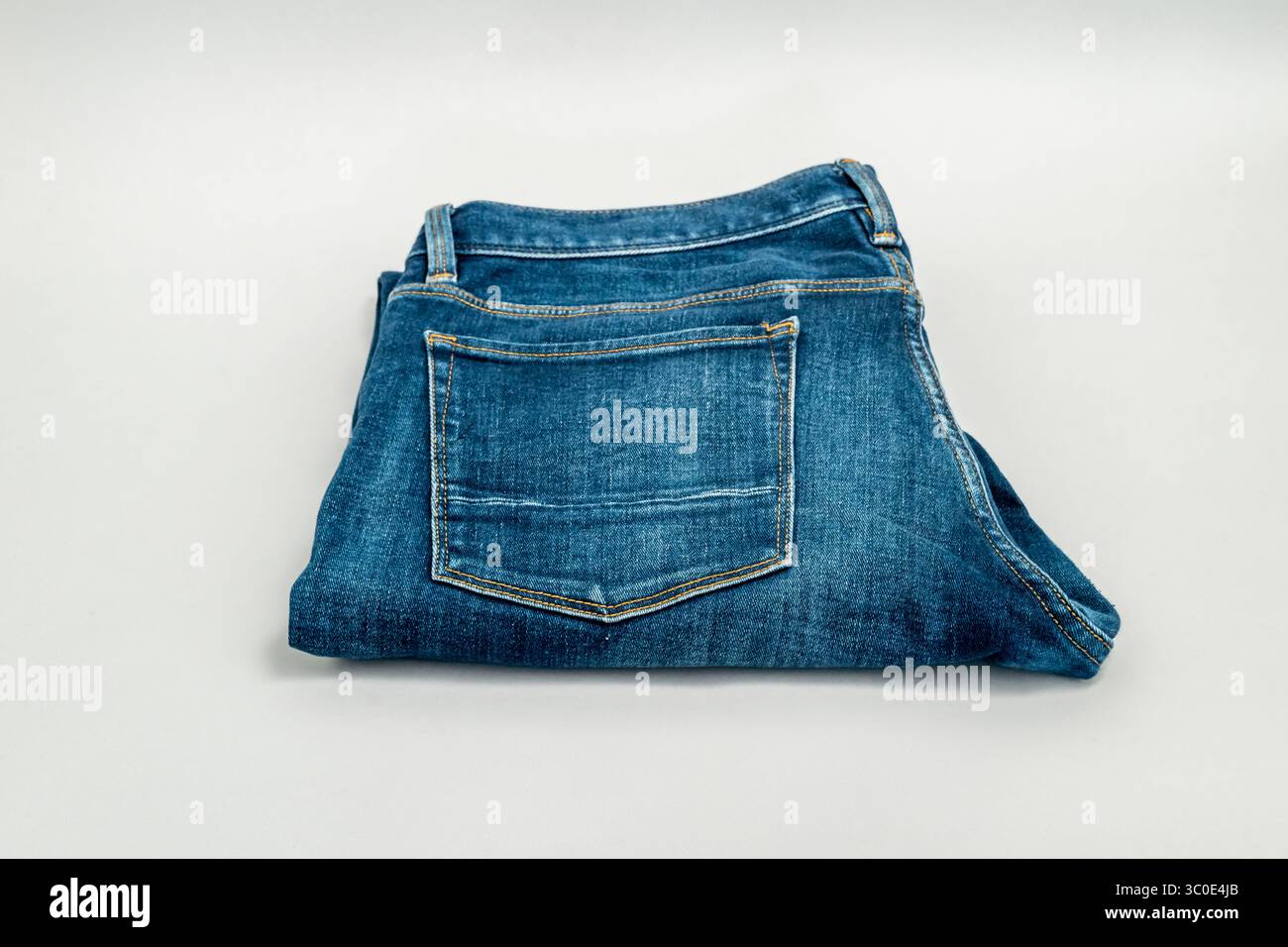 Un paio di jeans blu ripiegati e isolati su sfondo grigio. Foto Stock