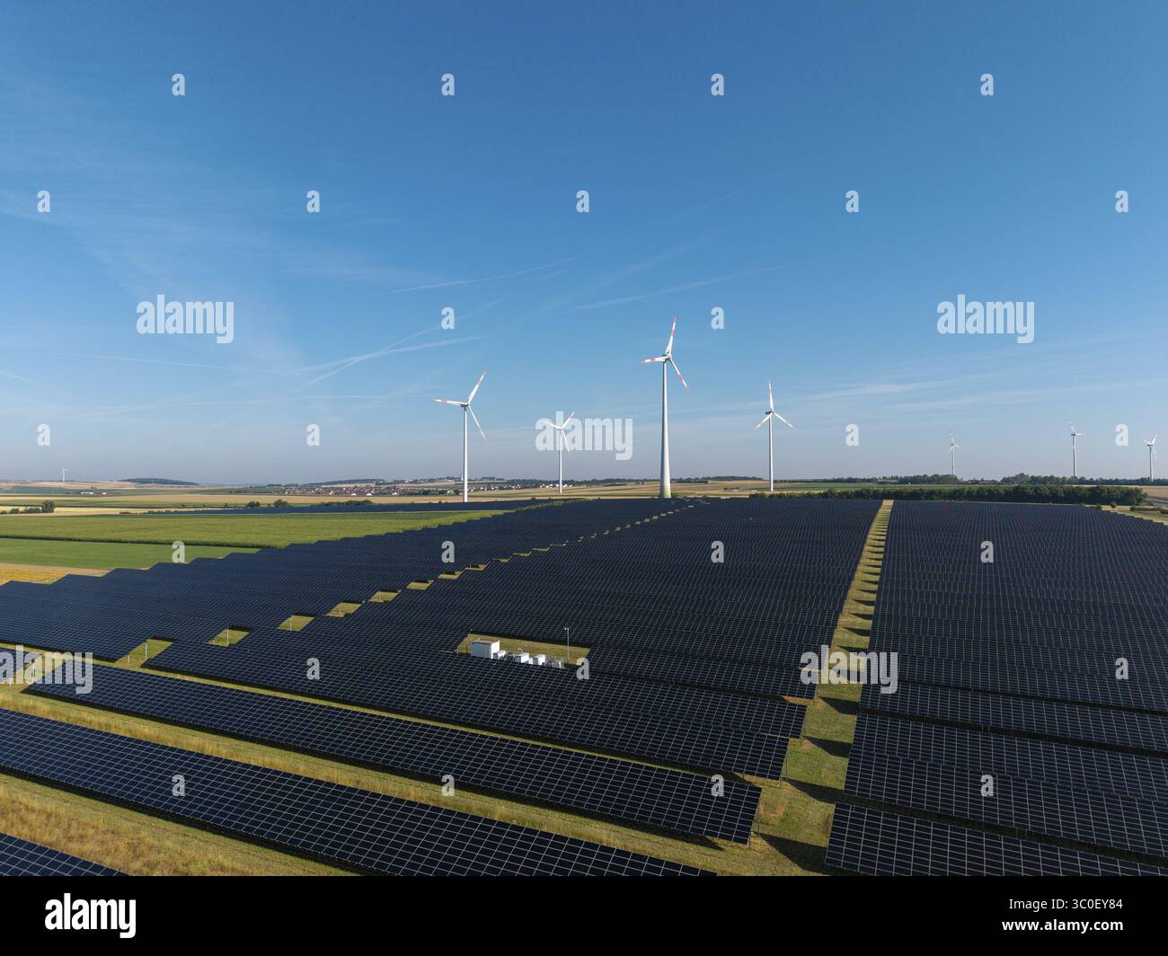 Ampi pannelli solari con turbine eoliche in un ambiente soleggiato, vicino a Kitzingen, bassa Franconia, Baviera, Germania Foto Stock