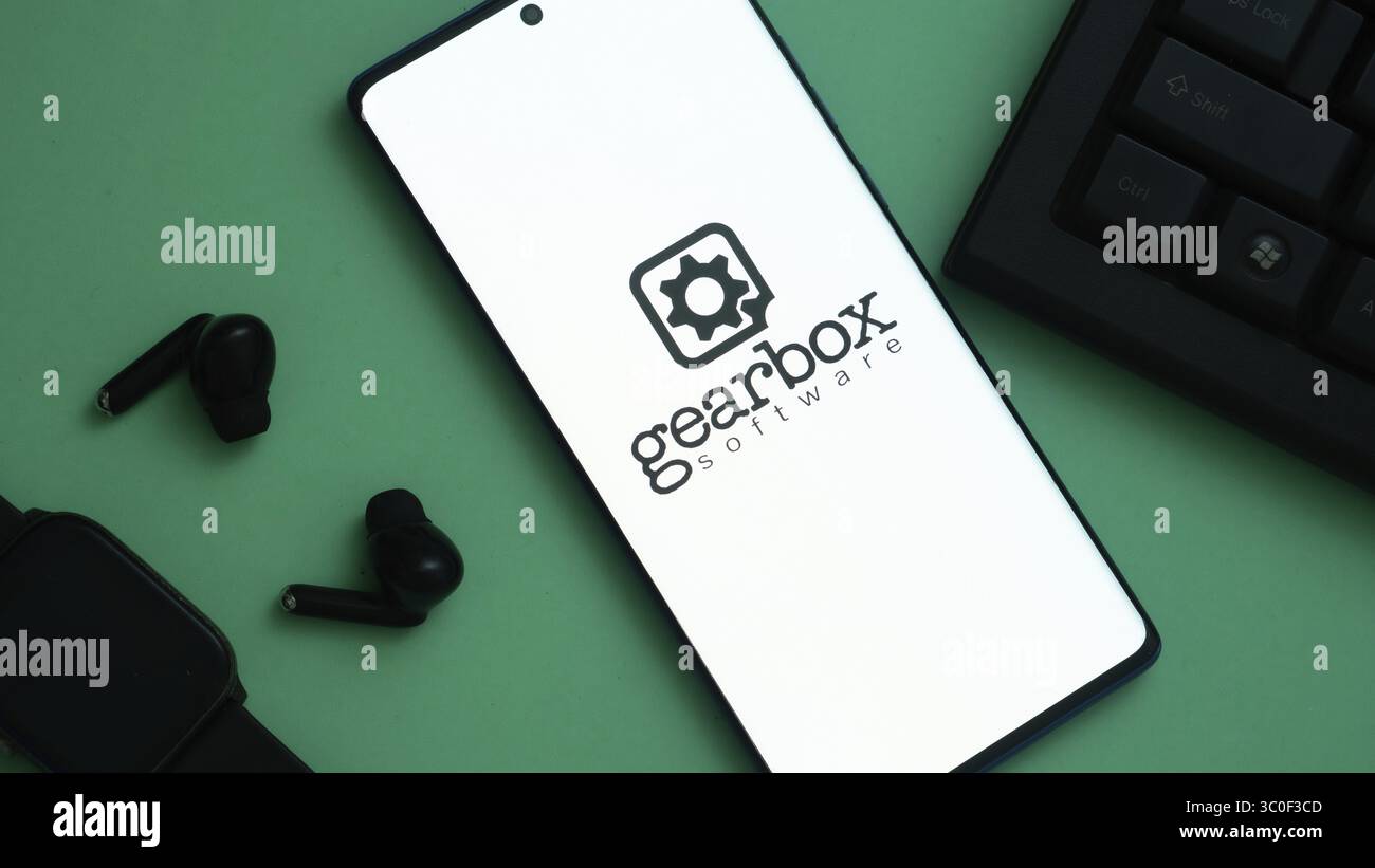 Logo del software Gearbox su uno smartphone con auricolari e tastiera nelle vicinanze Foto Stock