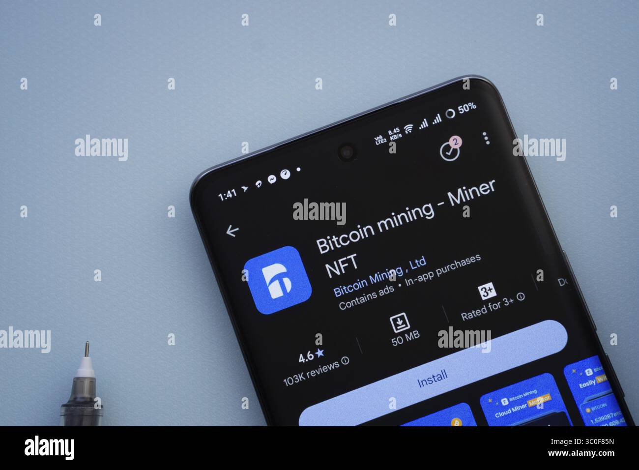 Dhaka, Bangladesh- 29 maggio 2025: Su una superficie blu, uno smartphone visualizza l'app Bitcoin mining all'interno del Google Play Store Foto Stock