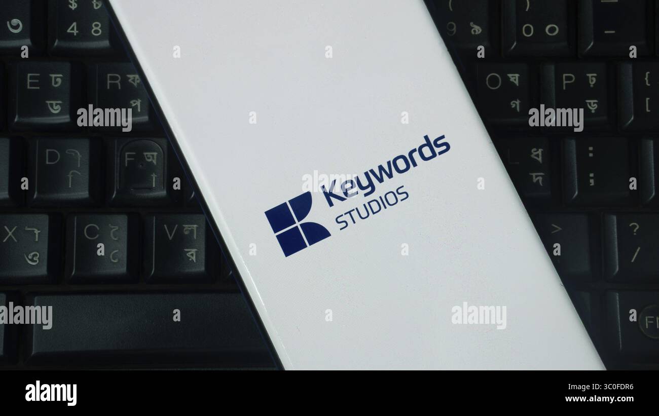 Elemento bianco con logo Keywords Studios posizionato su una tastiera nera Foto Stock
