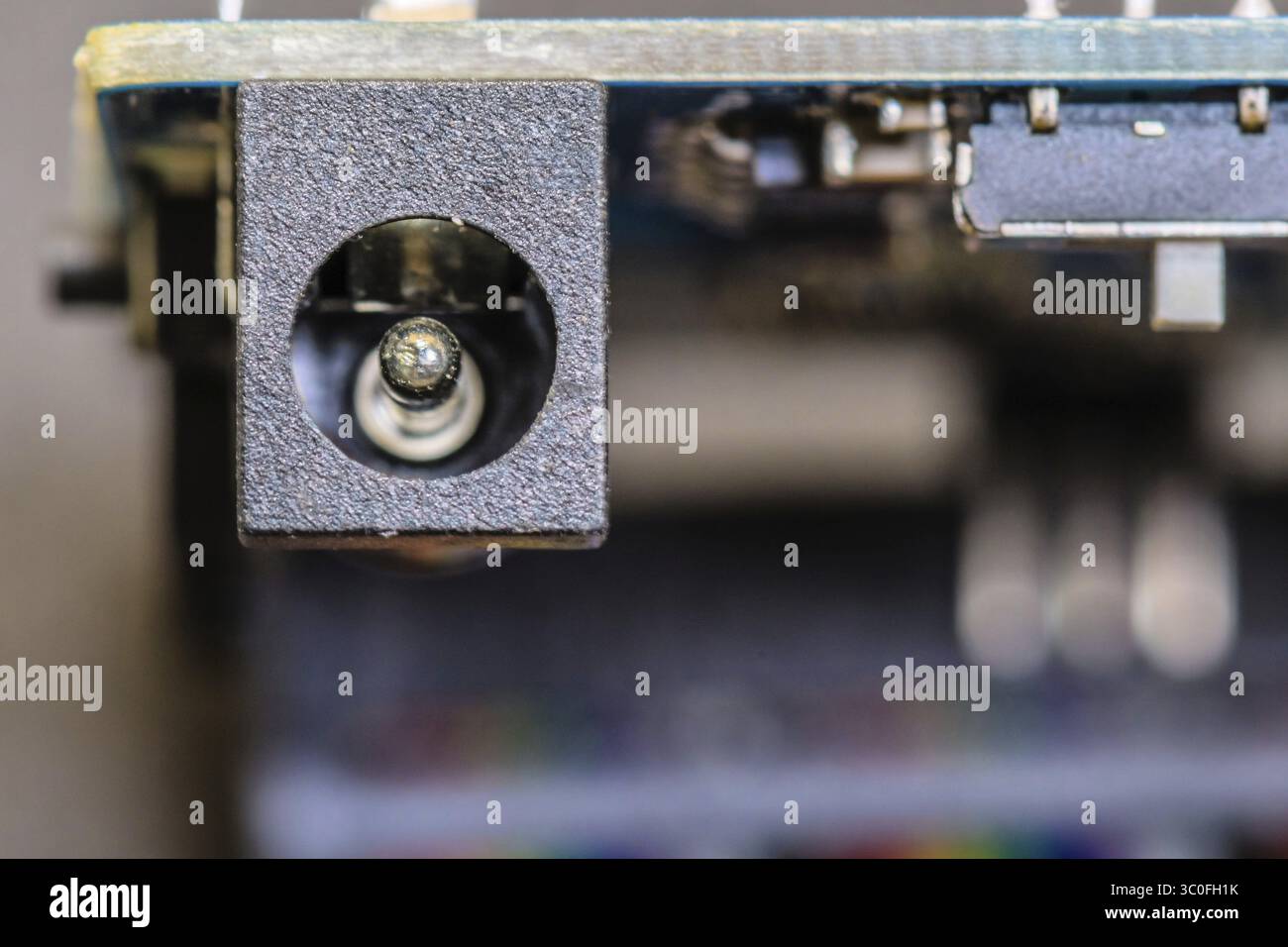 Primo piano di una porta del connettore di alimentazione su una scheda a circuito stampato, evidenziando il design elettronico Foto Stock