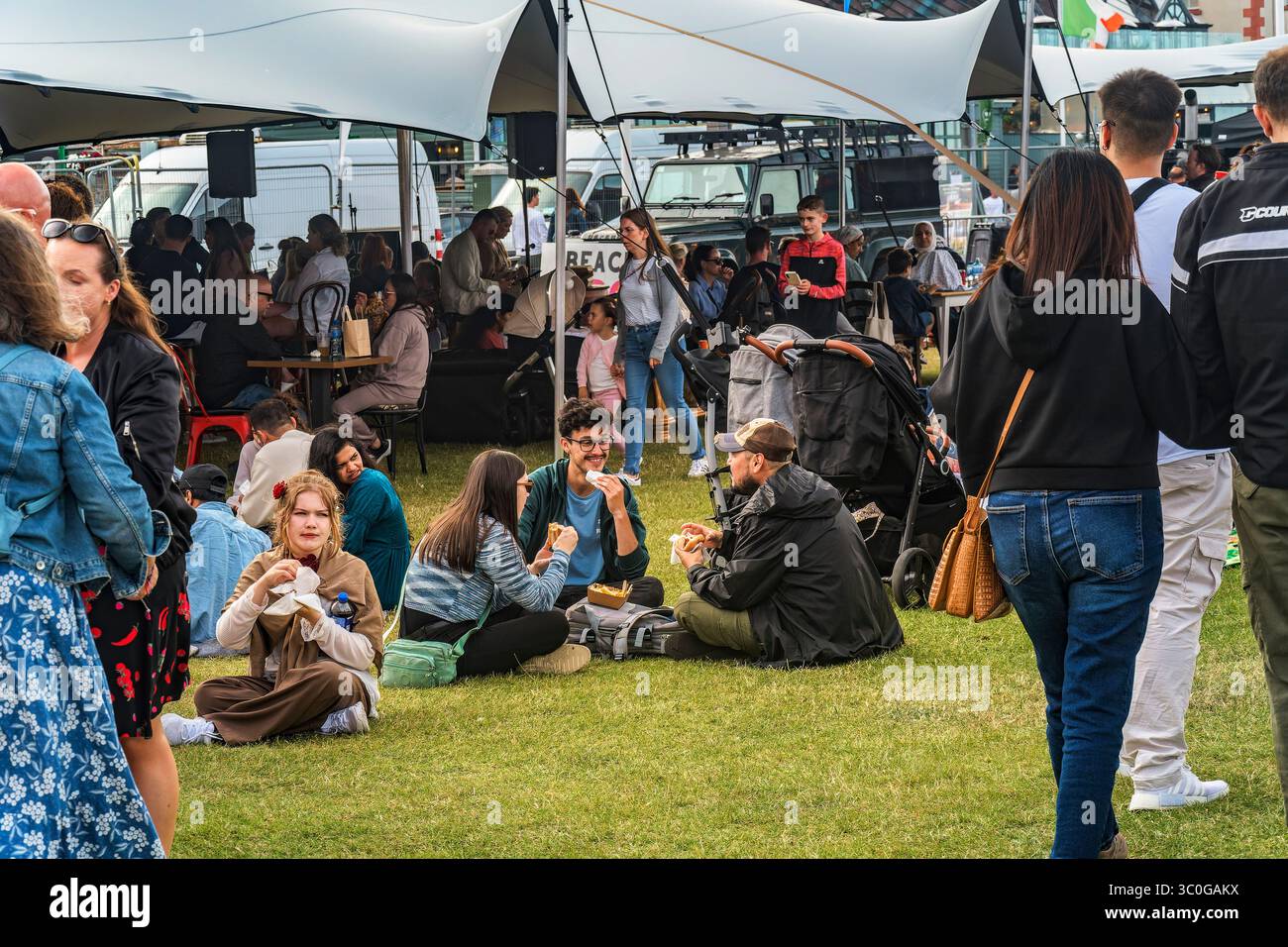 Gli amanti del festival si rilassano e fanno un picnic sull'erba al Bray Beach BBQ Festival, condividendo cibo e Risate – 19.07.2025 Foto Stock