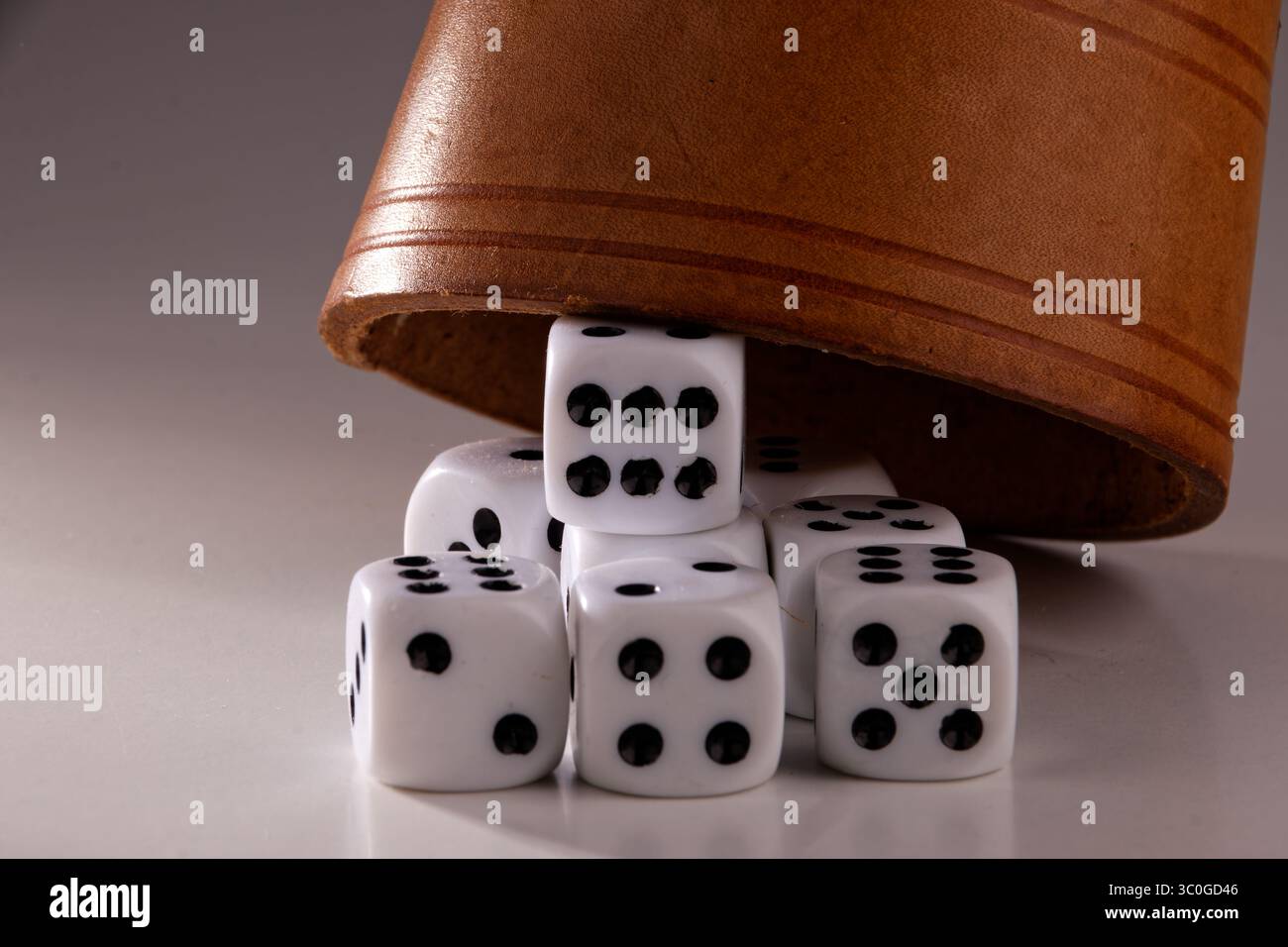 Vista dei dadi posizionati in modo casuale e di una tazza di puzzle dopo un lancio dei dadi Foto Stock