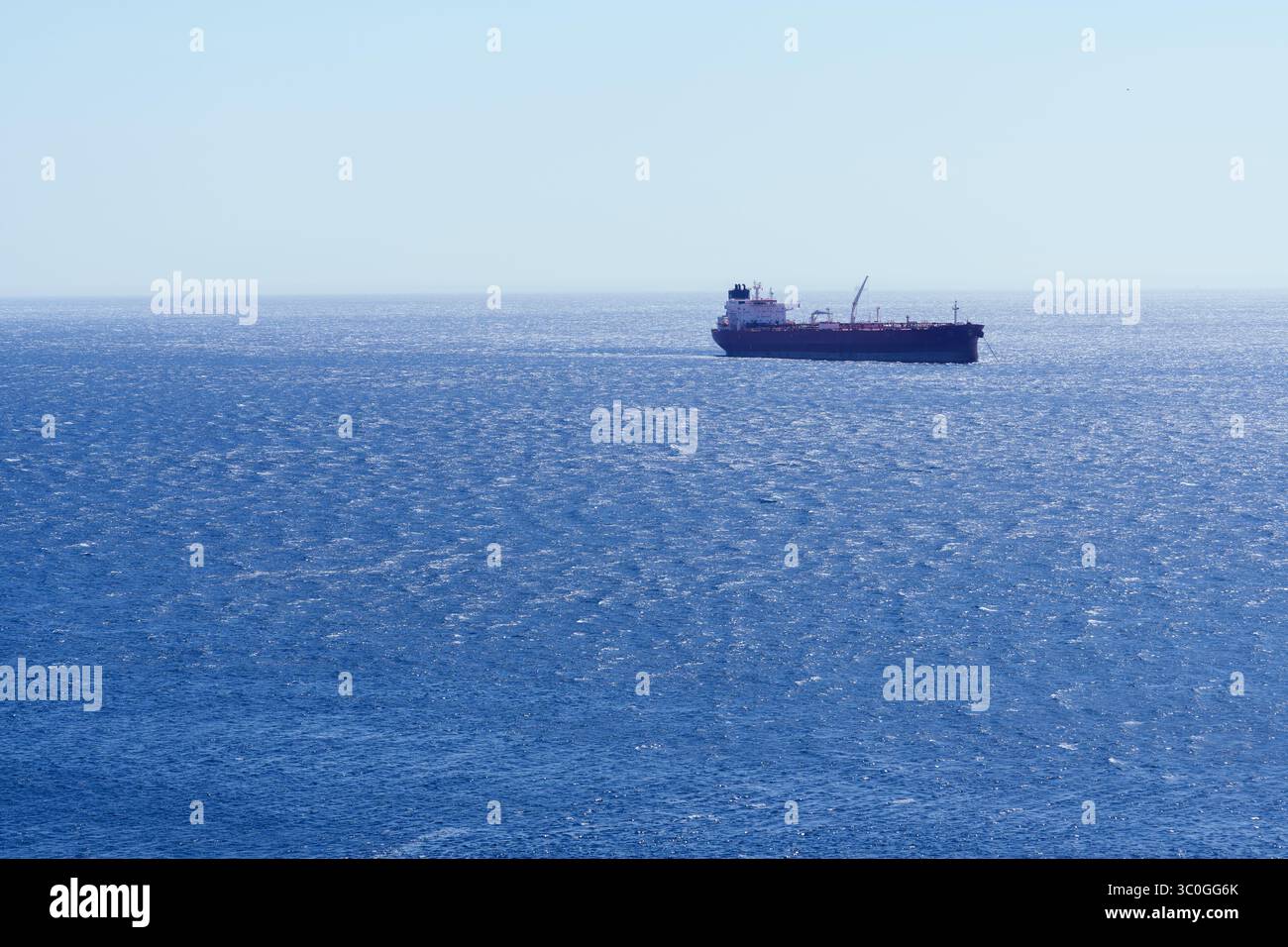 Nave da carico marittima che naviga in acque blu serene, rappresentando la navigazione internazionale e la connettività commerciale globale Foto Stock