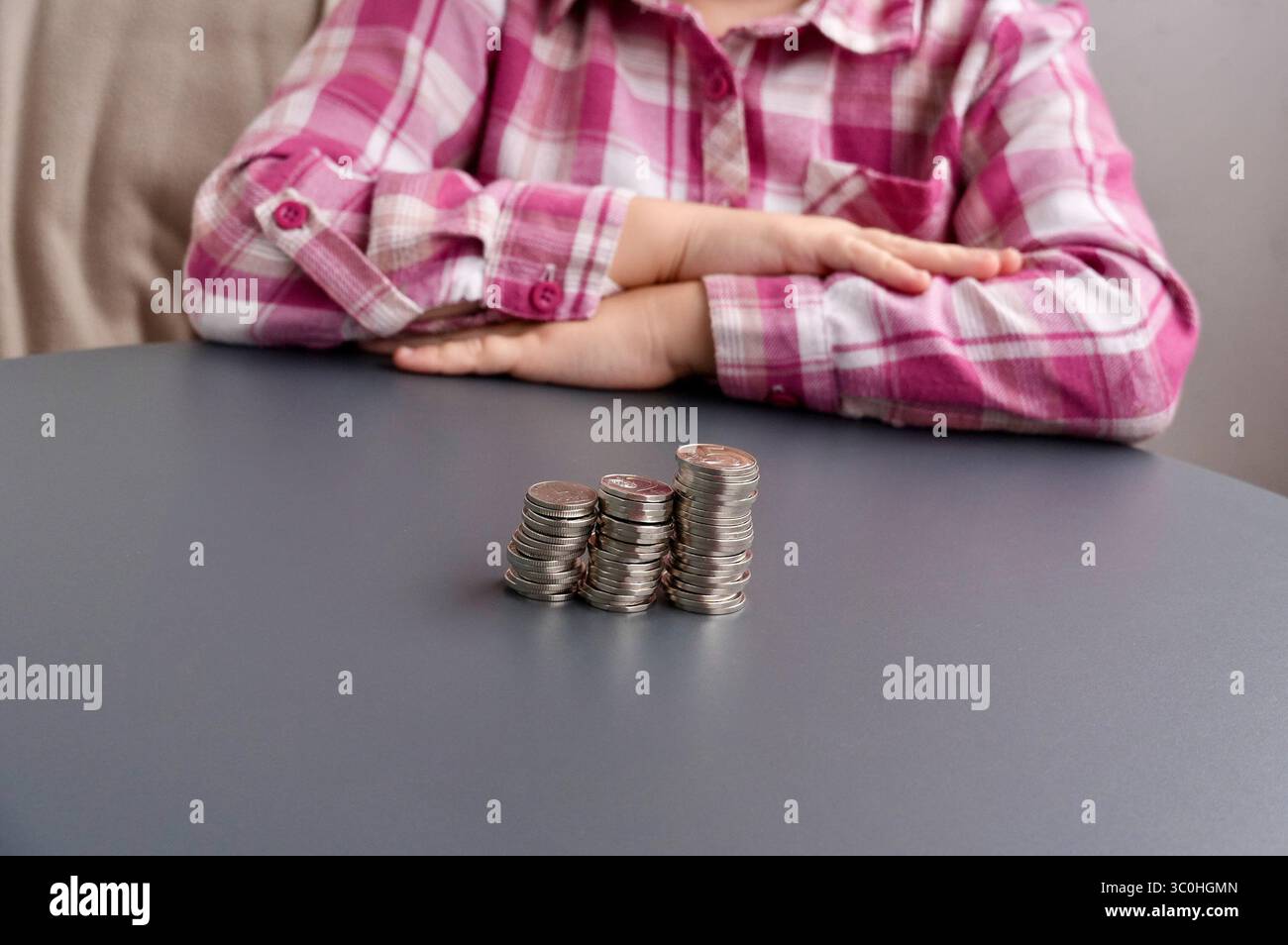 Mani di bambino con monete su sfondo grigio, primo piano Foto Stock