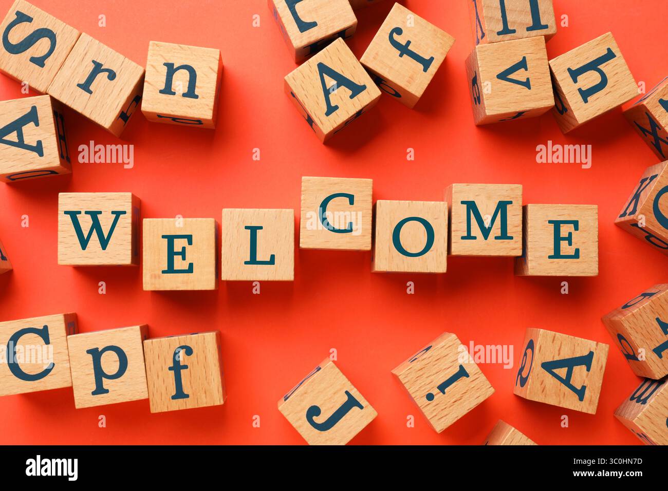 Parola di benvenuto fatta di cubi di legno su sfondo rosso, piatto Foto Stock