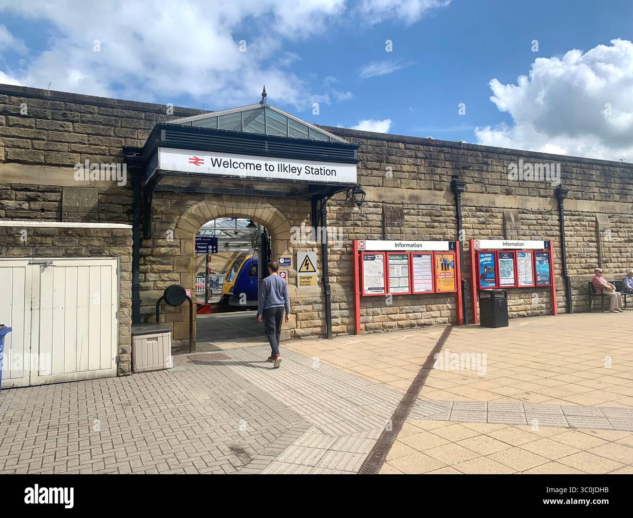 Ilkley Yorkshire stazione ferroviaria binario binario binario binario binario biglietteria cartelli vecchio stile tipo North People walking catch the train chair UK - Immagine stock catturata con smartphone