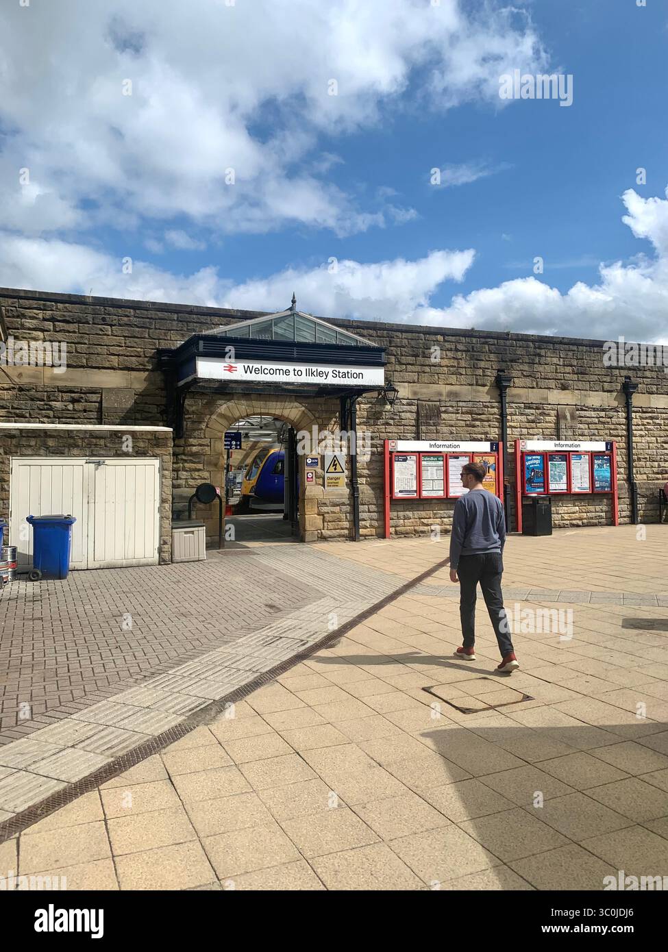 Ilkley Yorkshire stazione ferroviaria binario binario binario binario binario biglietteria cartelli vecchio stile tipo North People walking catch the train chair UK - Immagine stock catturata con smartphone