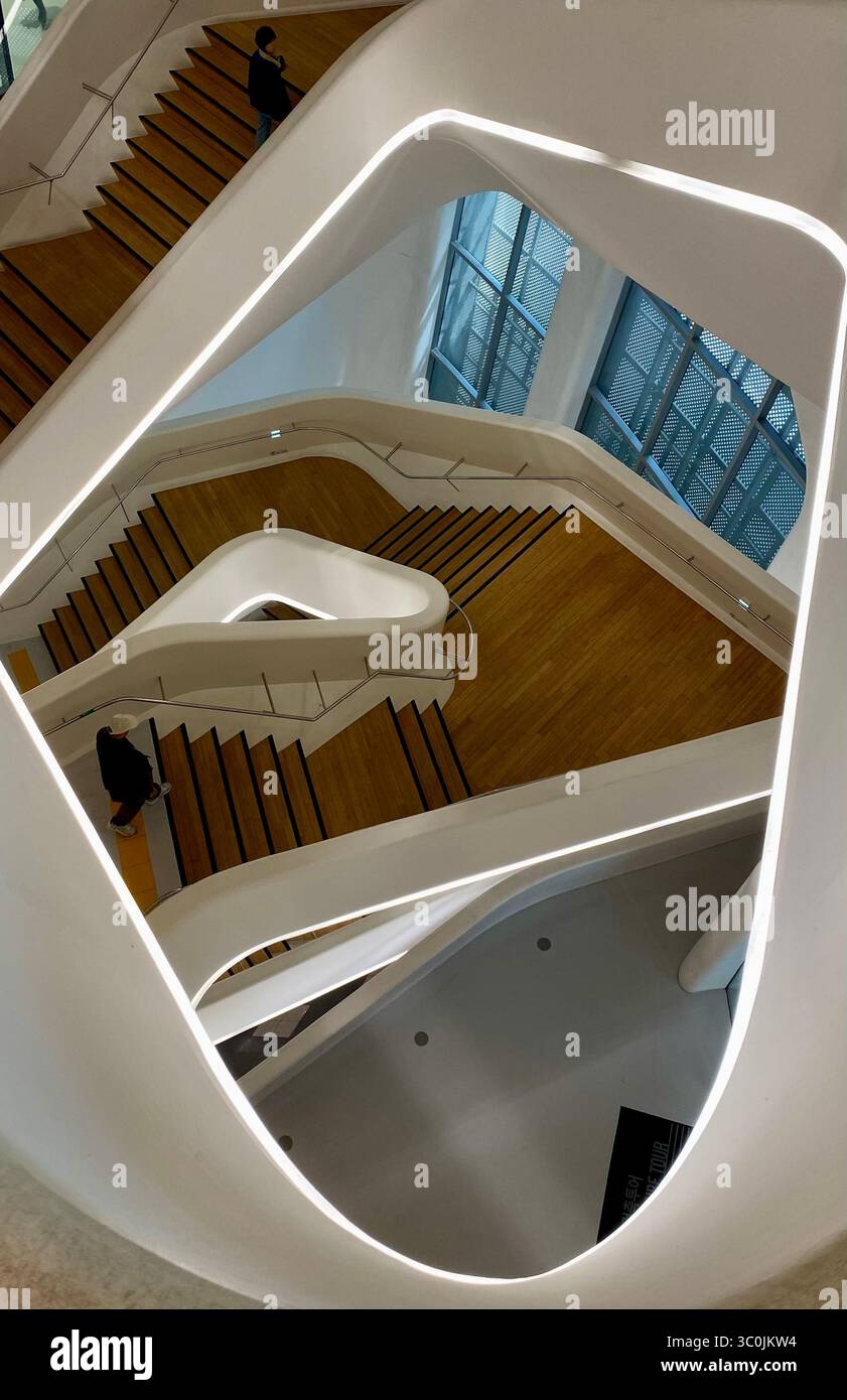 Moderna scala bianca curva con gradini in legno all'interno del DDP Dongdaemun Design Plaza, Seoul, Corea del Sud. Foto Stock