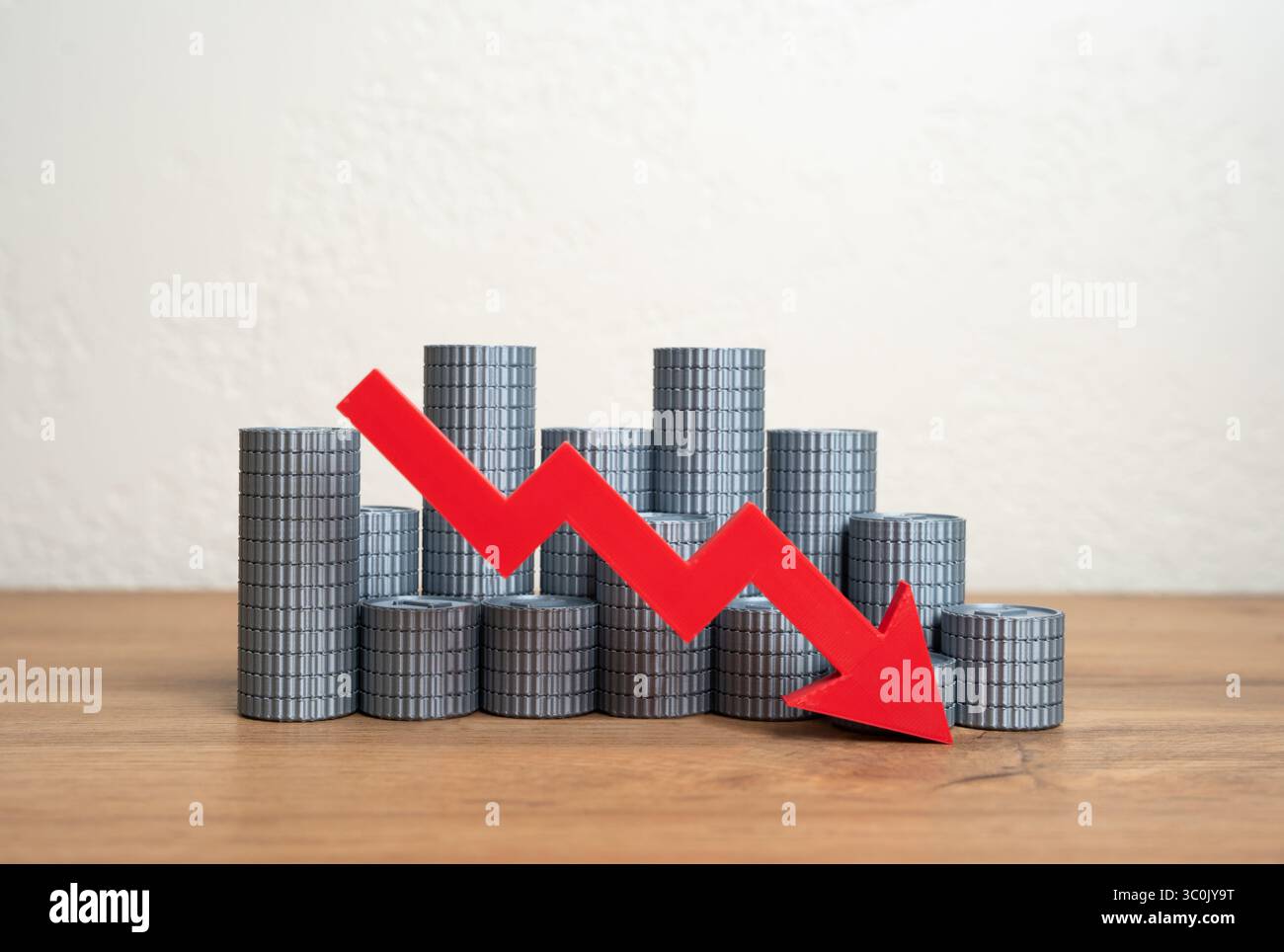 Una pila di monete e una freccia rossa rivolta verso il basso. Calo della stabilità finanziaria, perdita di reddito o riduzione dei risparmi. Recessione economica, investimenti insufficienti Foto Stock