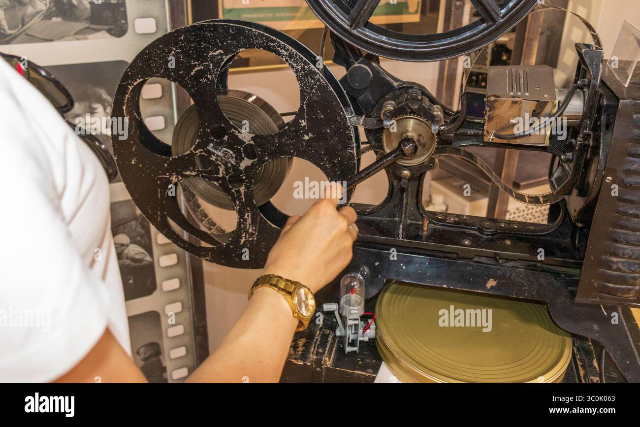 Donna che esamina un proiettore cinematografico d'epoca Foto Stock