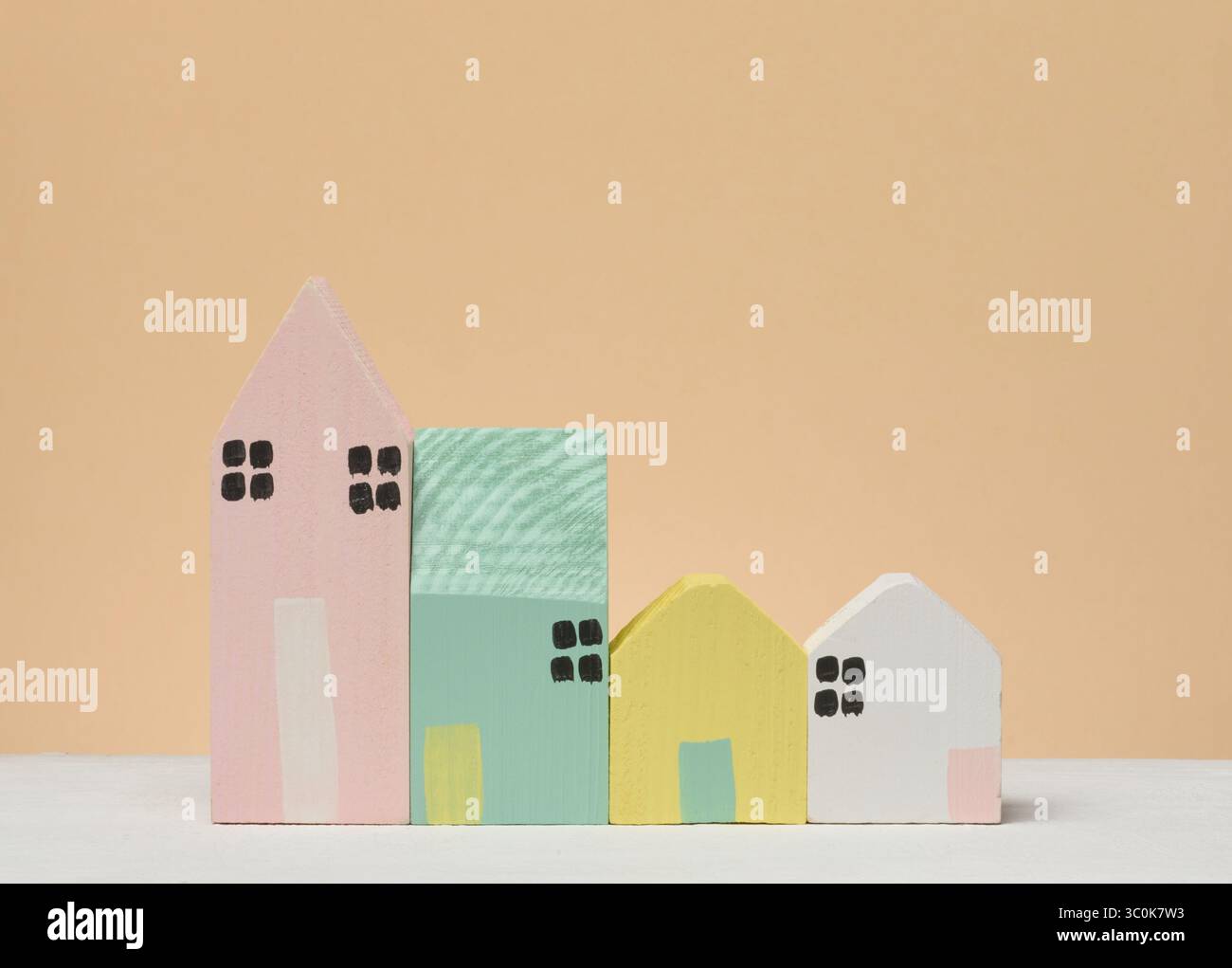 Una fila di case in legno stilizzate di diverse dimensioni e colori su una superficie leggera. Composizione del concetto immobiliare, di costruzione, di comunità o di casa Foto Stock
