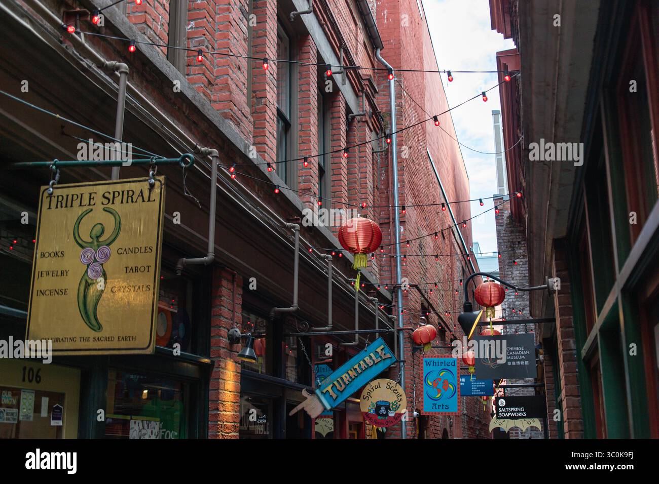 I colorati cartelli sospesi e le lanterne rosse fiancheggiano le strette pareti in mattoni di fan Tan Alley, un punto di riferimento culturale a Victoria. Foto Stock