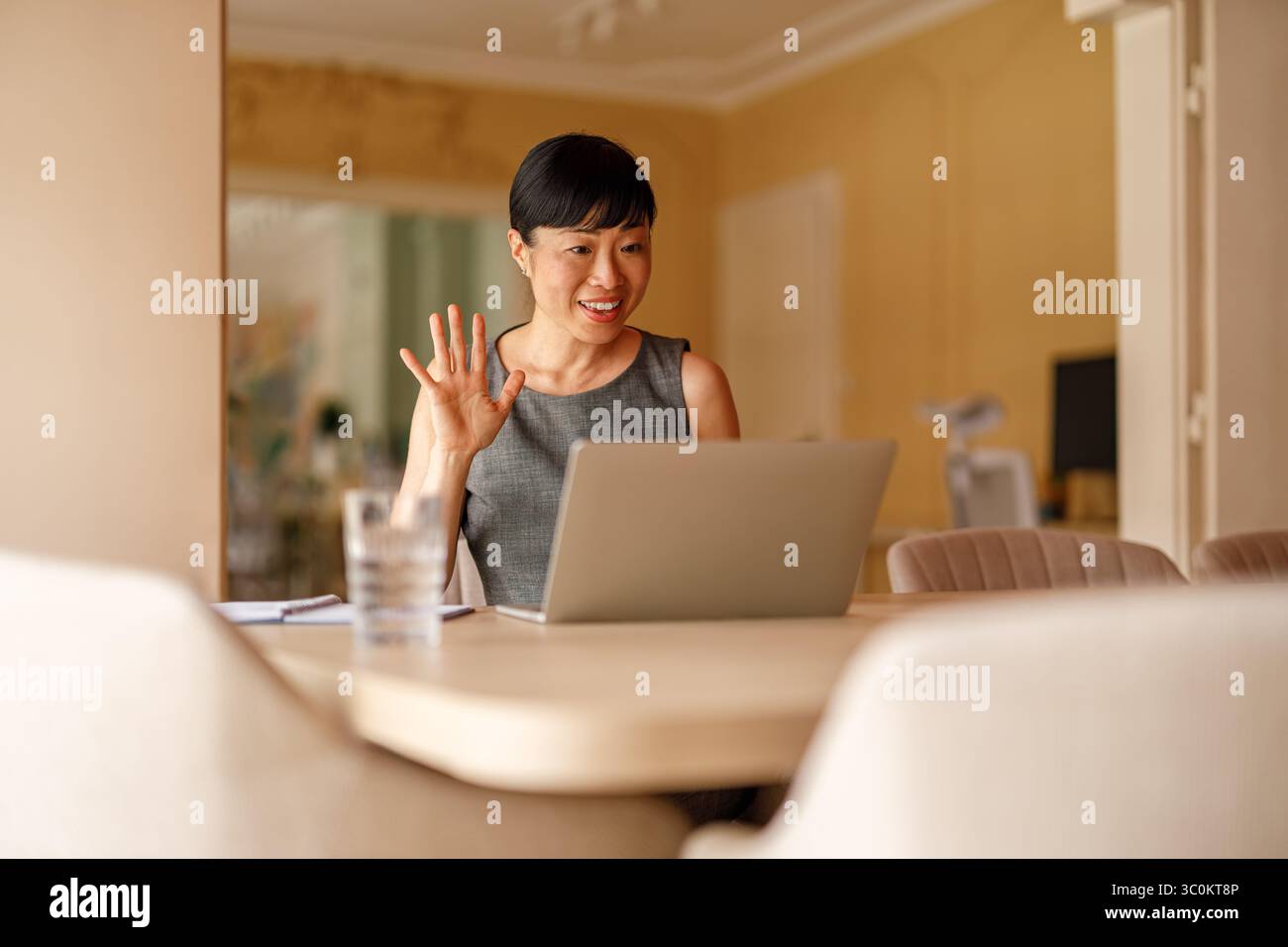 Donna d'affari felice che si muove mentre discute online durante una videochiamata sul laptop in ufficio Foto Stock