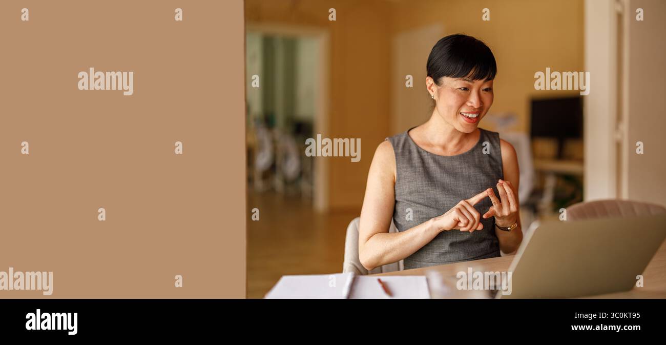 Donna sorridente professionista che parla di strategie aziendali su un notebook durante una videochiamata in un ufficio moderno Foto Stock