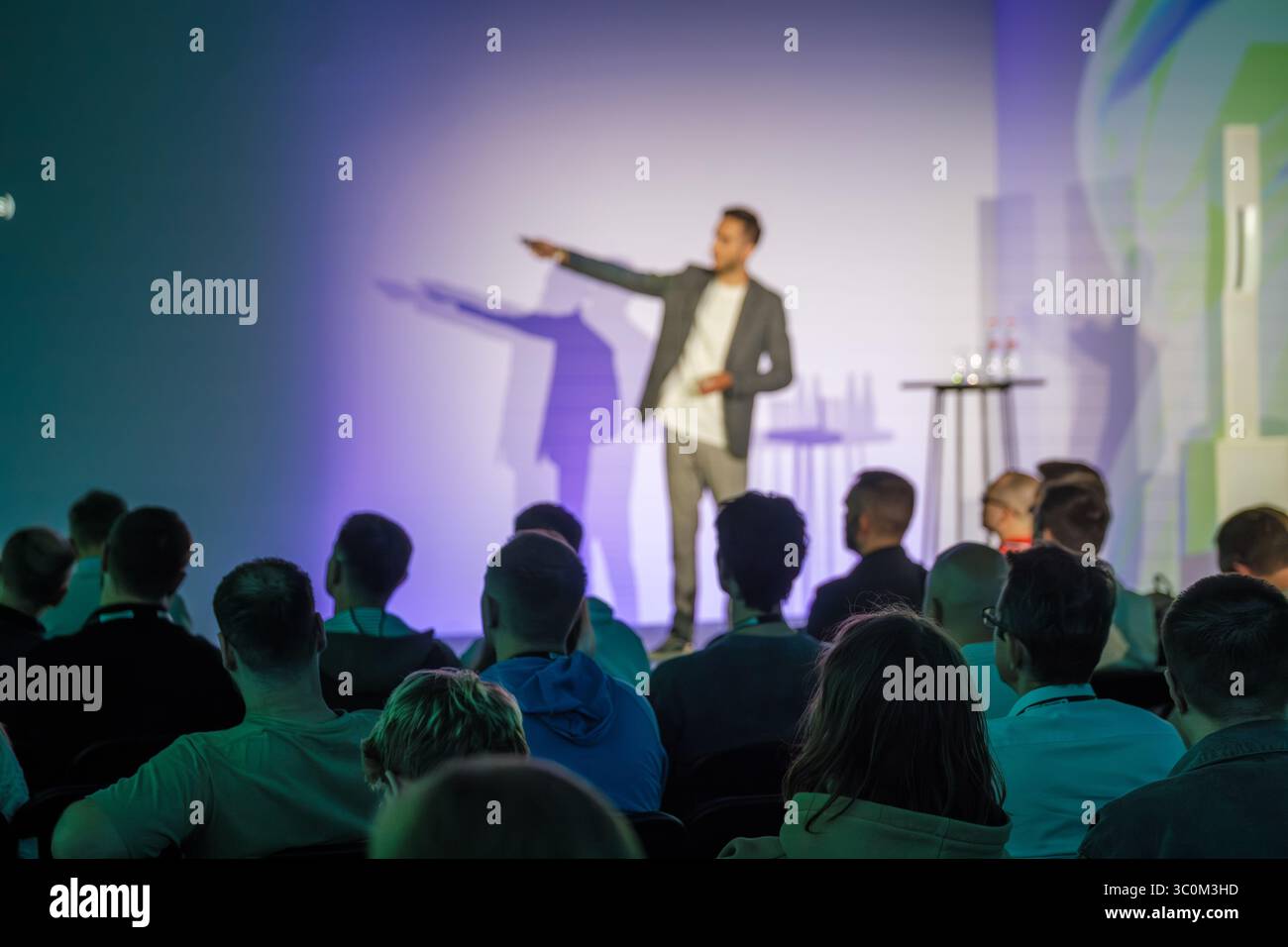 Speaker che indossa un abbigliamento casual da lavoro che presenta idee a un pubblico attento in un ambiente congressuale. Foto Stock