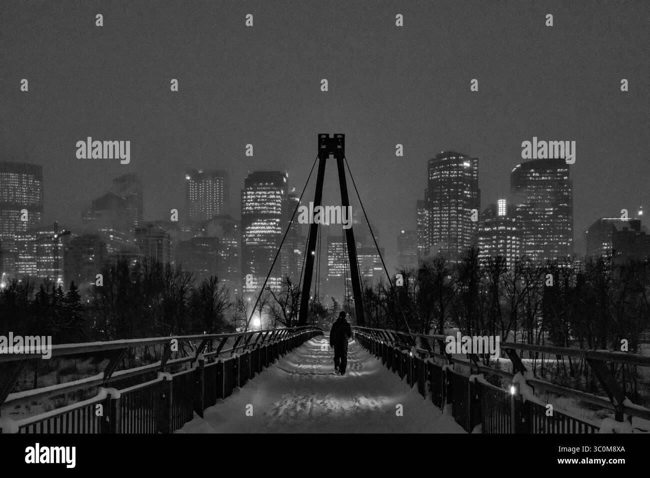 Un pendolare cammina sul ponte Bow River Pathways fino al centro di Calgary, Alberta, Canada, durante una nevicata mattutina. Foto Stock