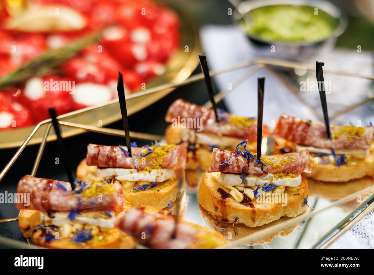 Pane tostato con formaggio e salame arrotolato. Ricoperto di erbe e fiori commestibili su un elegante vassoio Foto Stock