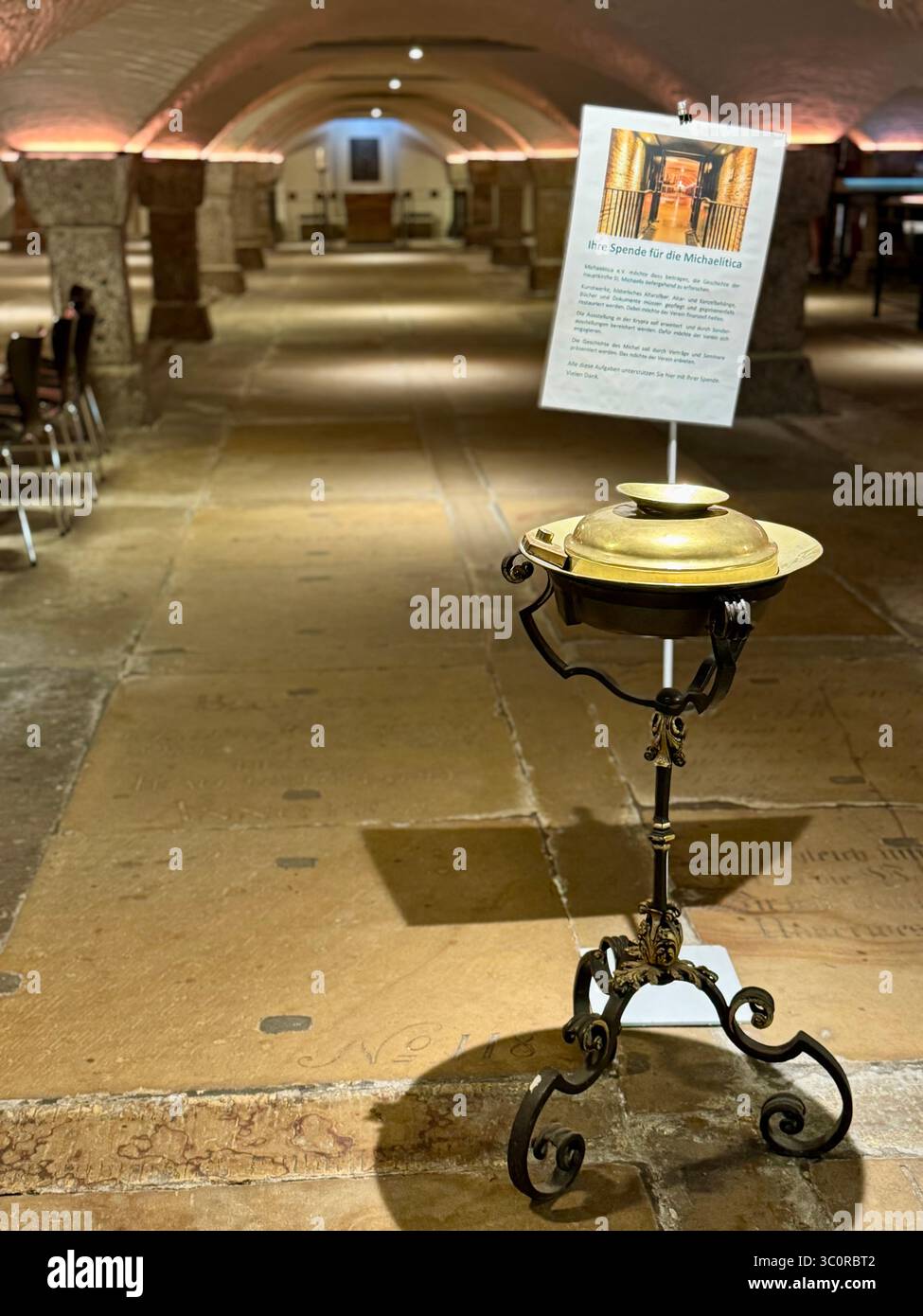 Vista interna di una storica cripta della chiesa di Amburgo, Germania, caratterizzata da una candela di preghiera e soffitti a volta in pietra. Foto Stock