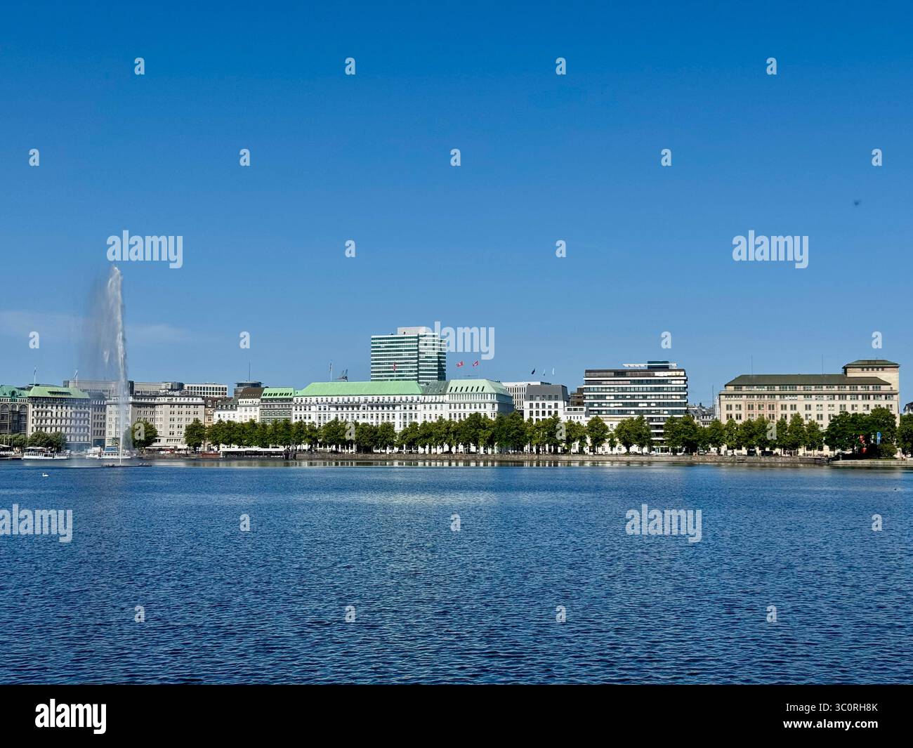 Panorama panoramico della città di Amburgo, Germania, con vista sul lago Alster con fontana ed edifici storici sotto un cielo azzurro. Foto Stock
