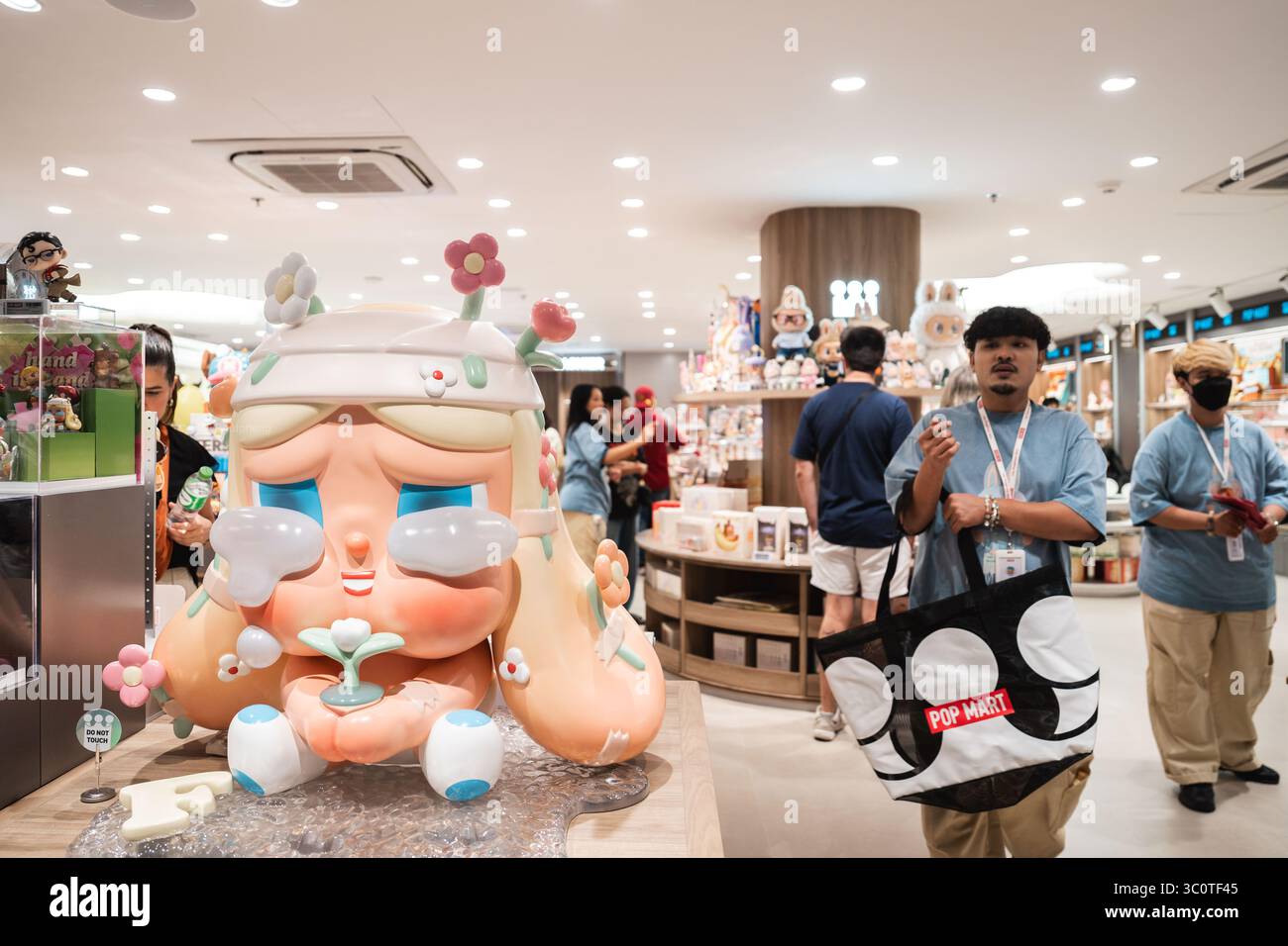 Una gigantesca scultura di un personaggio dagli occhi lacrimi che regge un germoglio è esposta al centro di un negozio POP MART. I collezionisti di scatole cieche di POP Mart hanno scatenato una mania culturale in tutta l'Asia e oltre, con i fan che inseguono figure rare come Labubu e Molly. Lanciato nel 2016 con le bambole Molly dall'artista di Hong Kong Kenny Wong, il marchio ha riscosso un enorme successo grazie alle vendite guidate dalla suspense. Attualmente presente in oltre 30 paesi e raggiungendo quasi 100 attraverso pop-up e partnership, Pop Mart ha trasformato i giocattoli di design in un fenomeno globale. (Foto di Ploy Phutpheng / SOPA Images/Sipa USA) Foto Stock