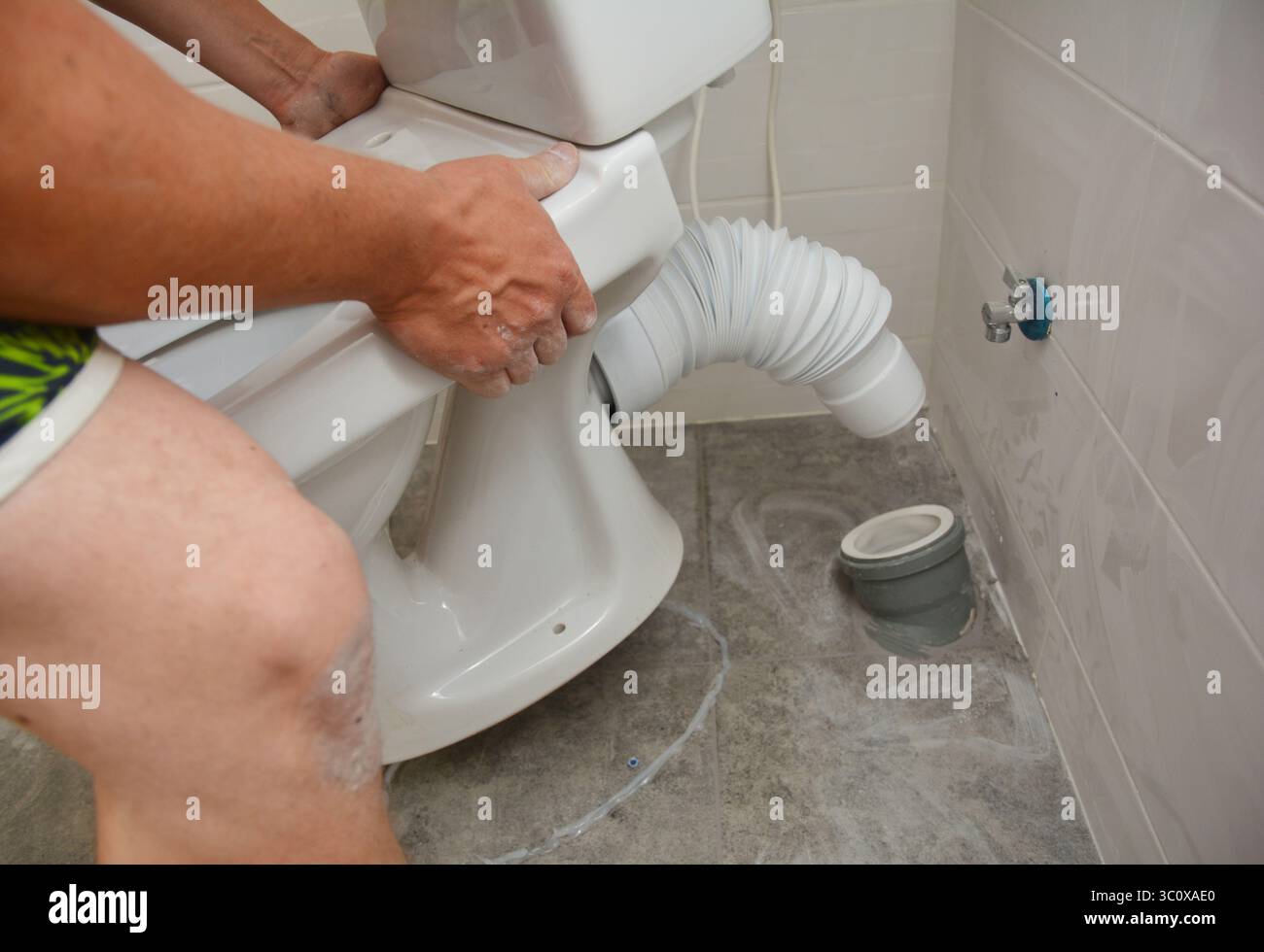 Riparatore che installa il wc a filo, la ciotola del wc nel bagno Foto Stock