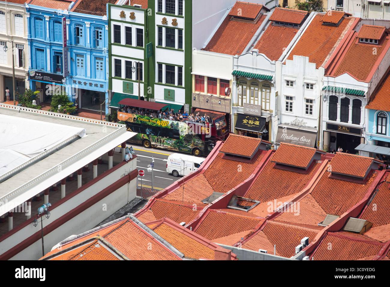 Vista aerea dei turisti sul Big Bus scoperto che visita Chinatown, Singapore. Cattura la vivace vita di strada, le attrazioni culturali e l'esperienza di viaggio urbana. Foto Stock
