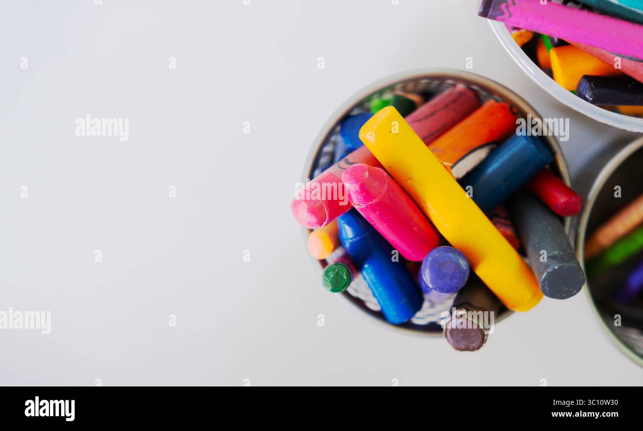 Pastelli di cera colorati in una lattina su uno sfondo bianco con immagine dello spazio di copia. Pastelli per bambini e matita a colori. Foto Stock
