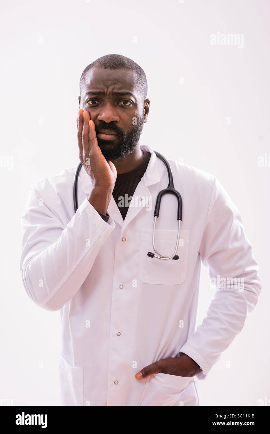 Ritratto di un paramedico maschile nero preoccupato che si sente preoccupato, che pensa e guarda la fotocamera. Studio girato su sfondo grigio. Foto Stock