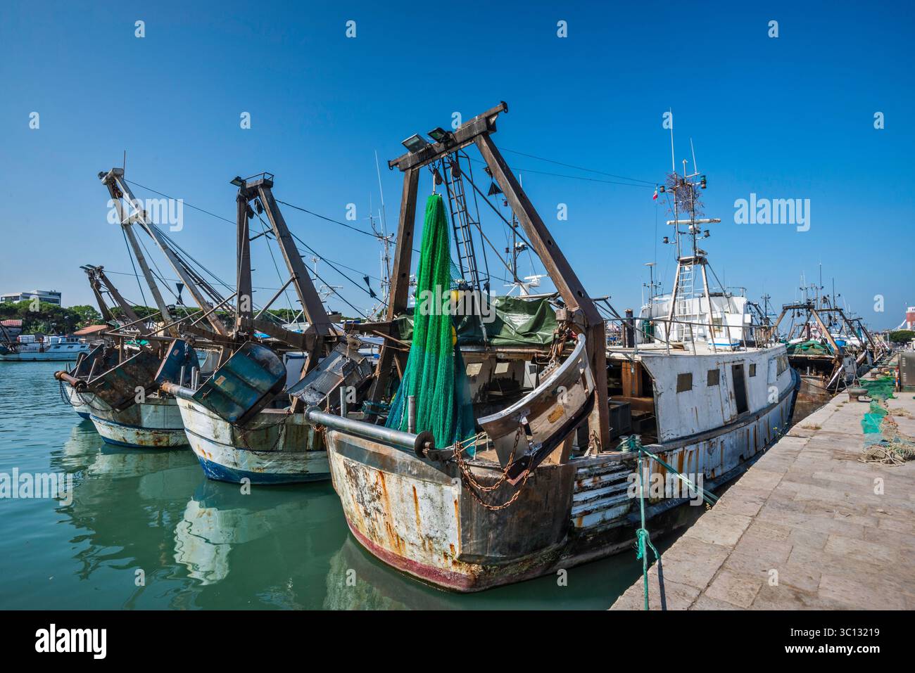 Draghe e reti a sterns delle barche da pesca ormeggiate al molo vicino alla foce del fiume Pescara nel porto di Pescara, regione Abruzzo, Italia Foto Stock