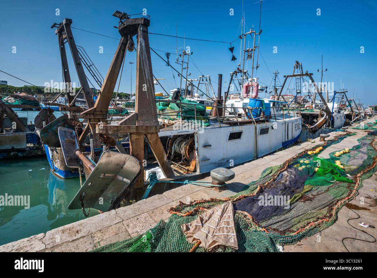 Draghe e reti a sterns delle barche da pesca ormeggiate al molo vicino alla foce del fiume Pescara nel porto di Pescara, regione Abruzzo, Italia Foto Stock
