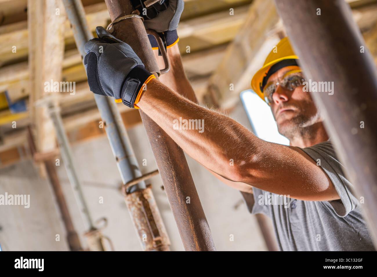 I lavoratori qualificati che indossano l'attrezzatura di sicurezza regolano una trave di supporto in metallo in un cantiere durante le ore di lavoro diurne. Il sito presenta un fep di ristrutturazione Foto Stock
