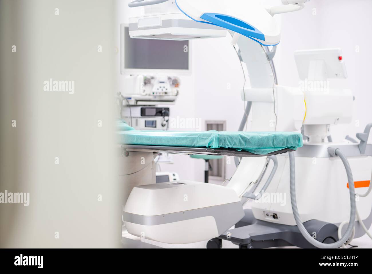 Una sala per visite mediche ben illuminata mette in mostra attrezzature chirurgiche avanzate e un tavolo operatorio pronto per le procedure in una struttura sanitaria. Foto Stock