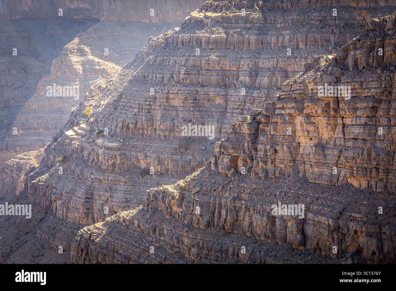 Formazioni rocciose e strati di roccia e strati con creste illuminate dal sole, vista ravvicinata del pendio roccioso del deserto degli Emirati Arabi Uniti, incrinato e secco. Foto Stock